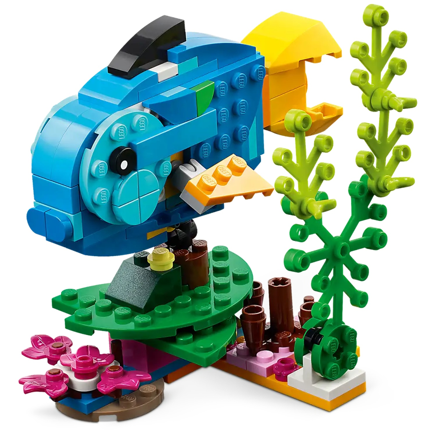 Een Lego vis, blauw met gele vinnen, staat boven een groene koraalbasis met roze bloemen en groen zeewier. De achtergrond is wit.