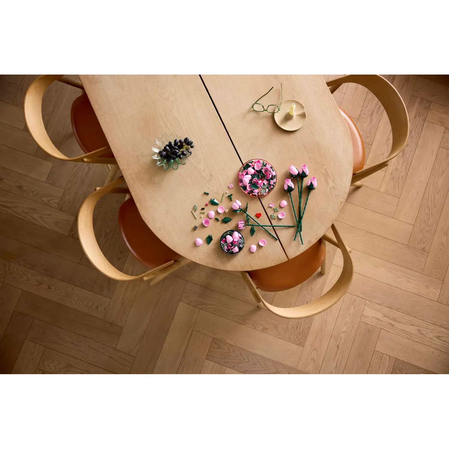 Overzicht van een houten tafel met bloemen, druiven, glazen en stoelen. De vloer is van hout.
