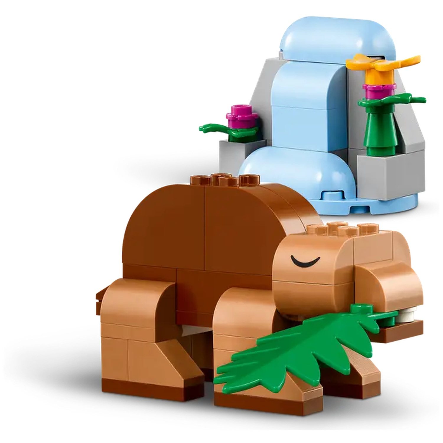 Un hippopotame Lego marron mangeant une feuille verte, avec une structure de cascade bleue et grise en arrière-plan.