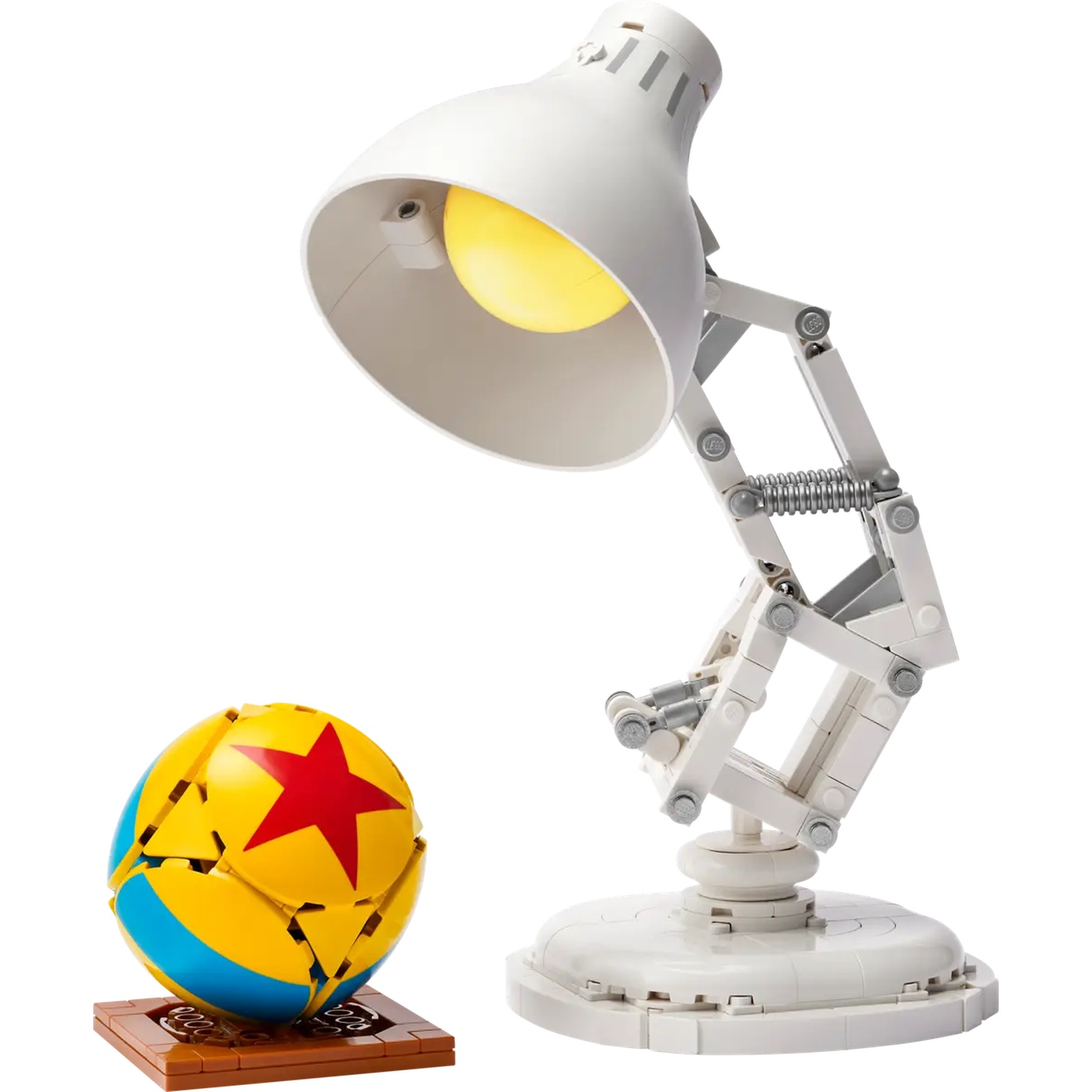 A white desk lamp with a yellow light is next to a ball with a red star and blue stripe on a brown stand.
