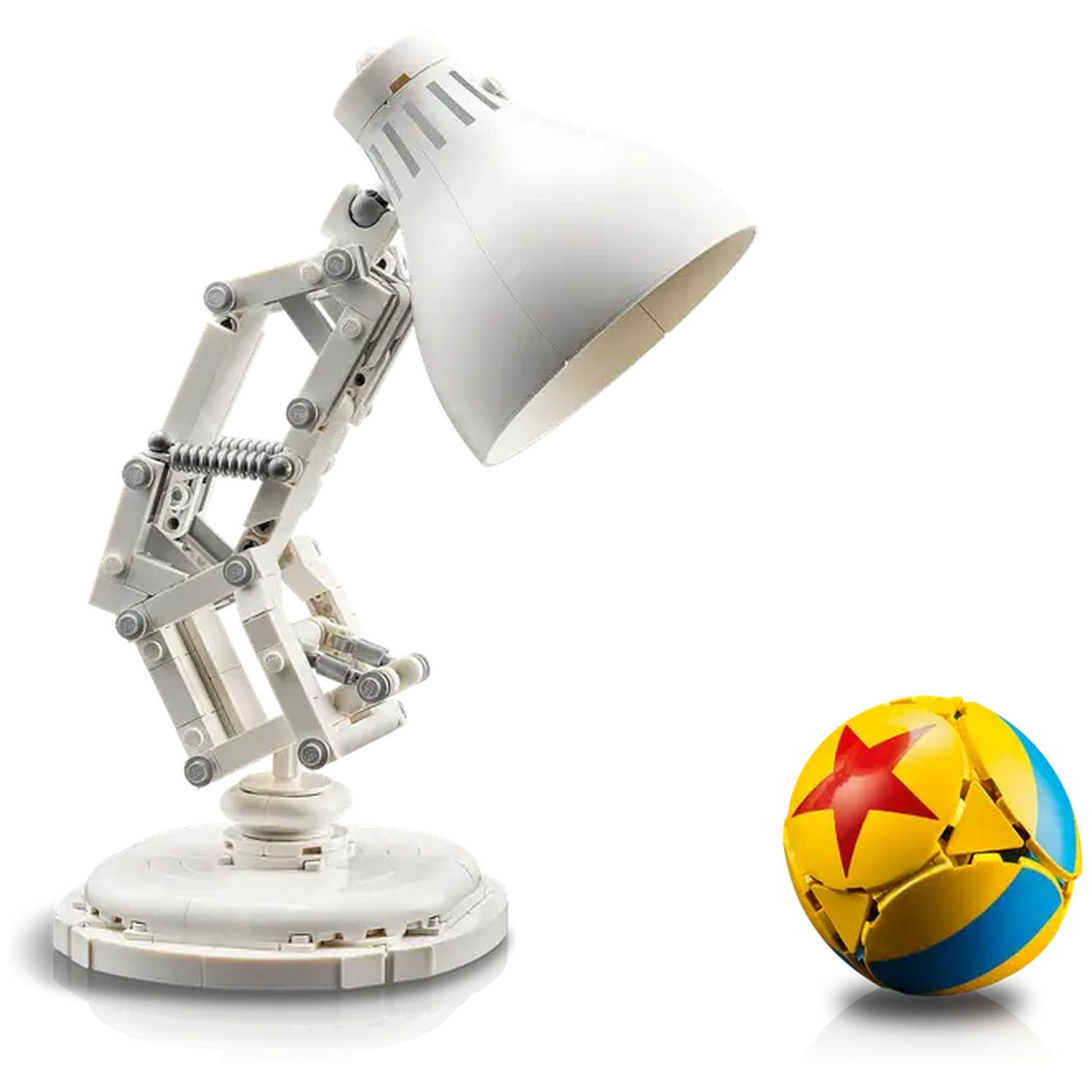 A white desk lamp and a ball. The lamp has a white shade and a movable arm. The ball is yellow with a red star and blue stripes.