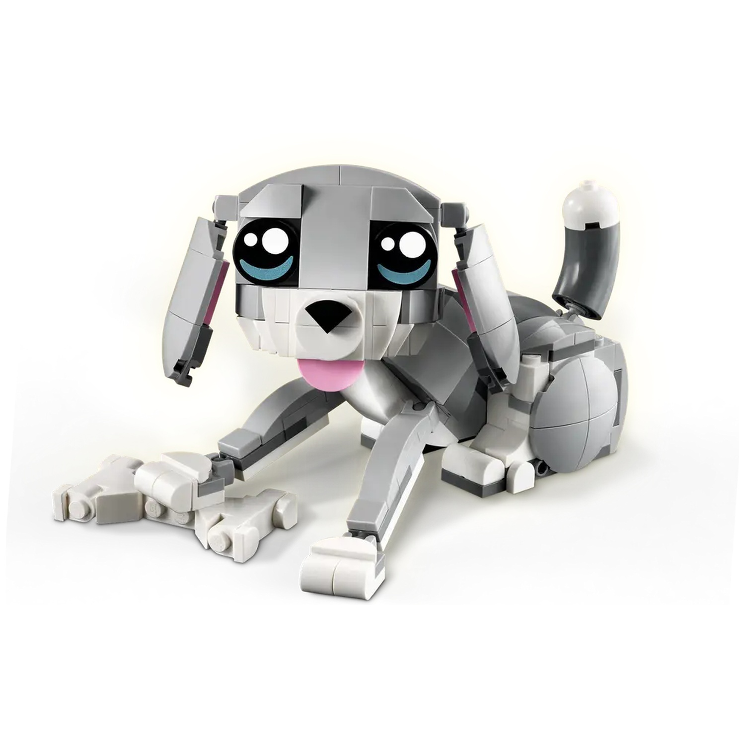 A Lego dog, gray and white with a pink tongue, large eyes, and a curved tail, sits on a white surface.