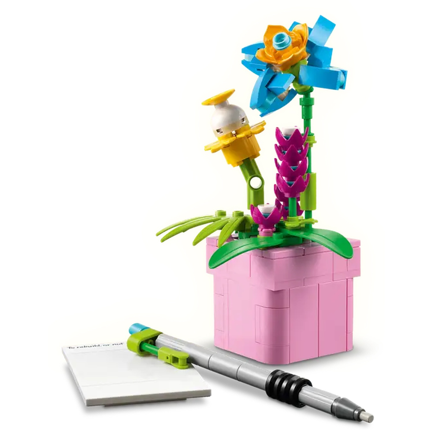 Een Lego bloempot met een bloem, een pen en een notitieblok. De bloem is blauw en oranje. De pot is roze. De pen is grijs.