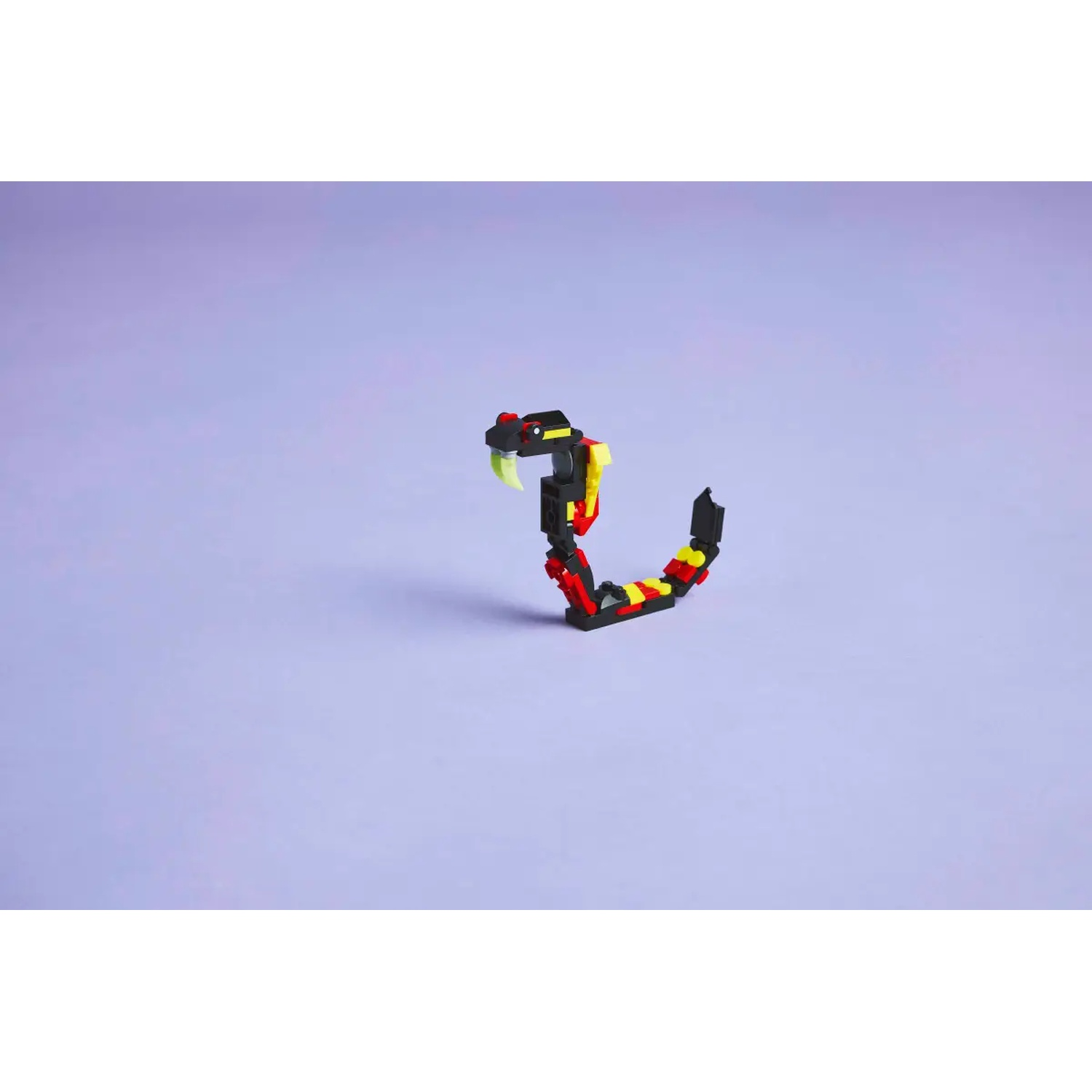 A toy snake made of blocks. It has a black body with red, yellow stripes. The head is black with a green fang and a red stripe.