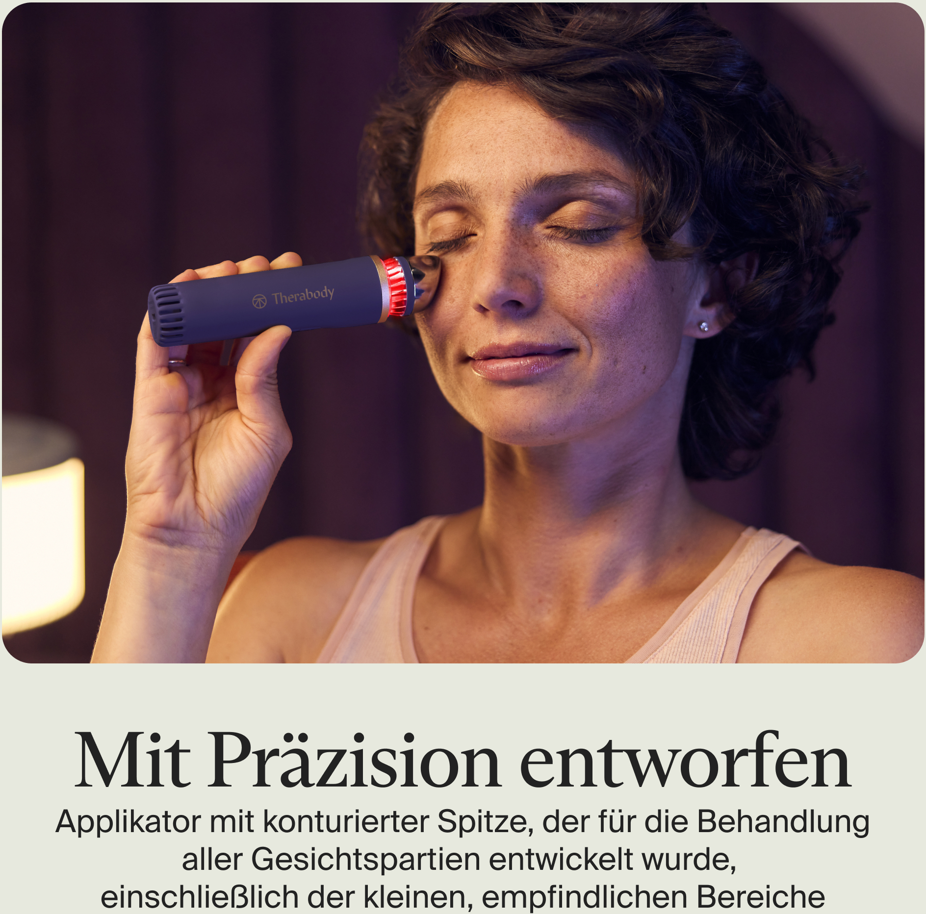 Frau hält ein blaues Gerät in der Nähe ihres Auges. Das Gerät hat ein rotes Licht. Sie hat die Augen geschlossen.