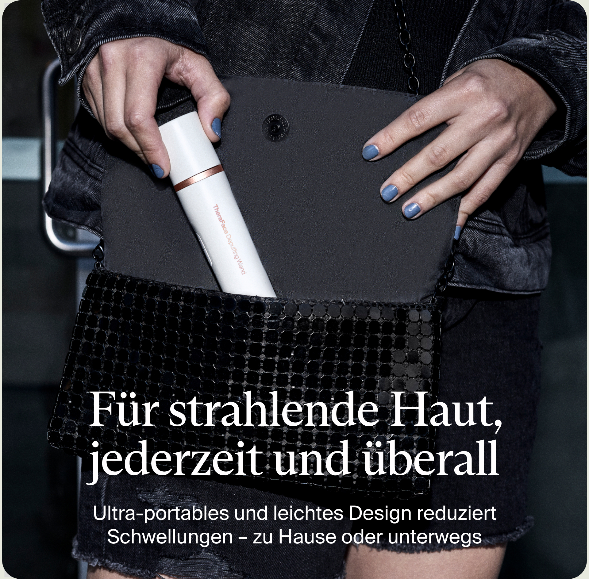 Eine Person hält einen weißen TheraFace Depuffing Wand in einer schwarzen Handtasche. Die Person trägt eine Jeansjacke und blaue Nägel.