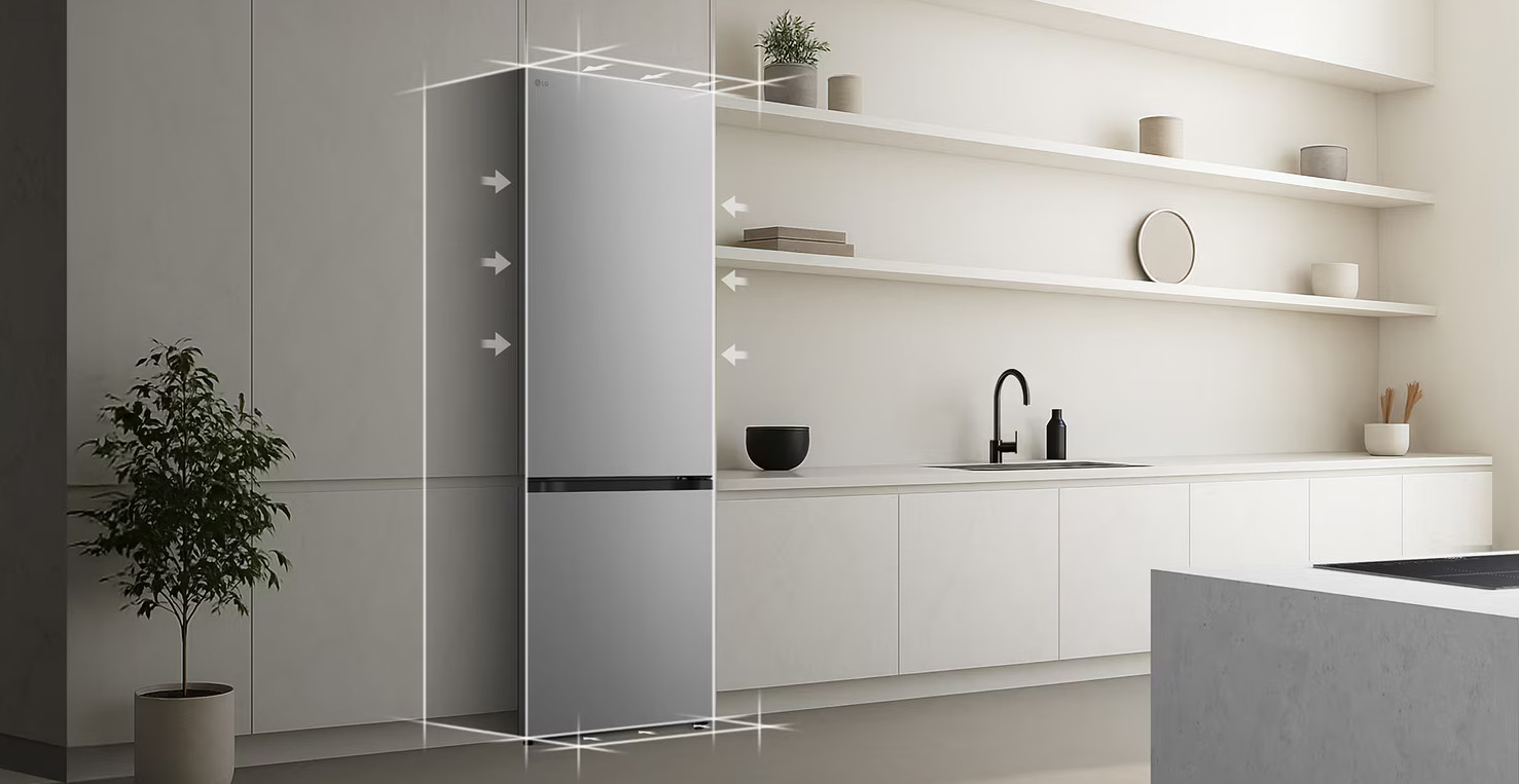 Nowoczesna kuchnia z szarą lodówką. Widoczna jest roślina i półki z dekoracjami. Obecne są białe szafki i zlew.