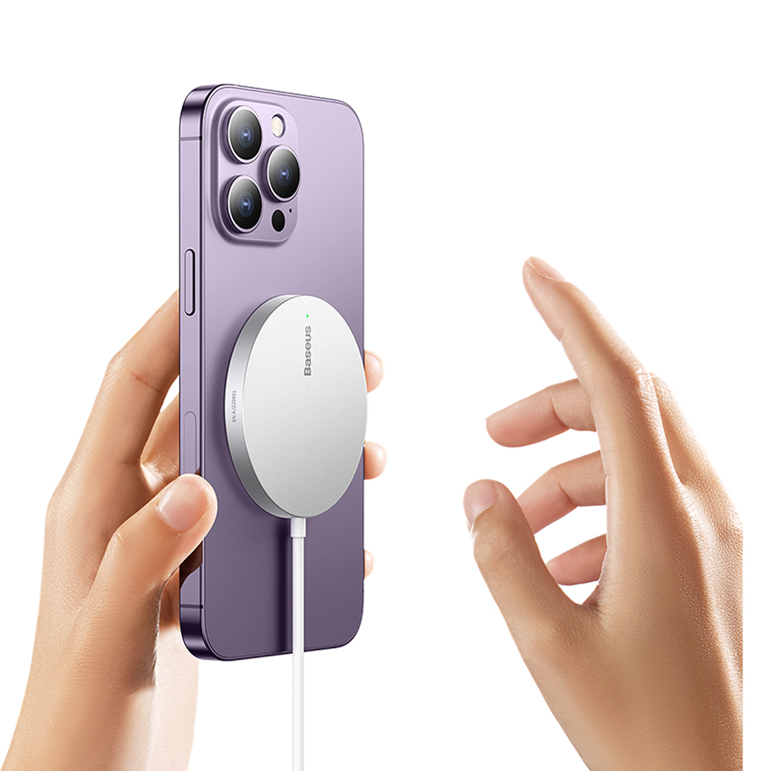 Una mano sostiene un teléfono morado con un cargador blanco adjunto. Otra mano apunta al teléfono.