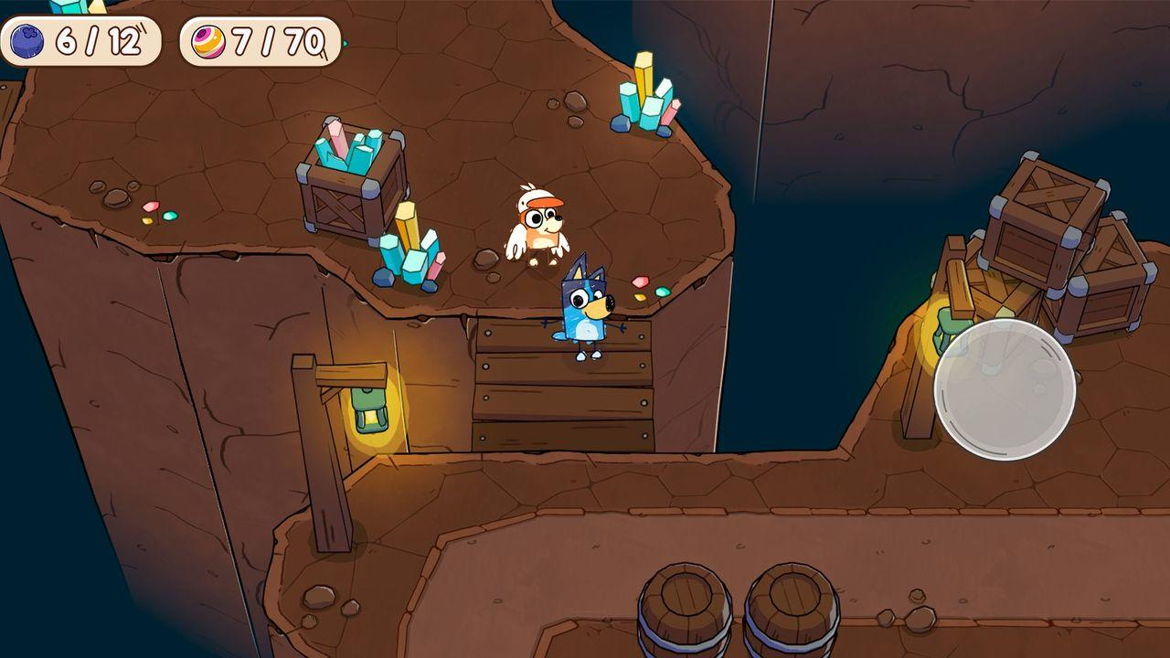 Bluey und eine Vogel-Figur stehen auf einer Holzbrücke in einer Höhle. In der Szene gibt es Kisten mit Kristallen und Fässern.