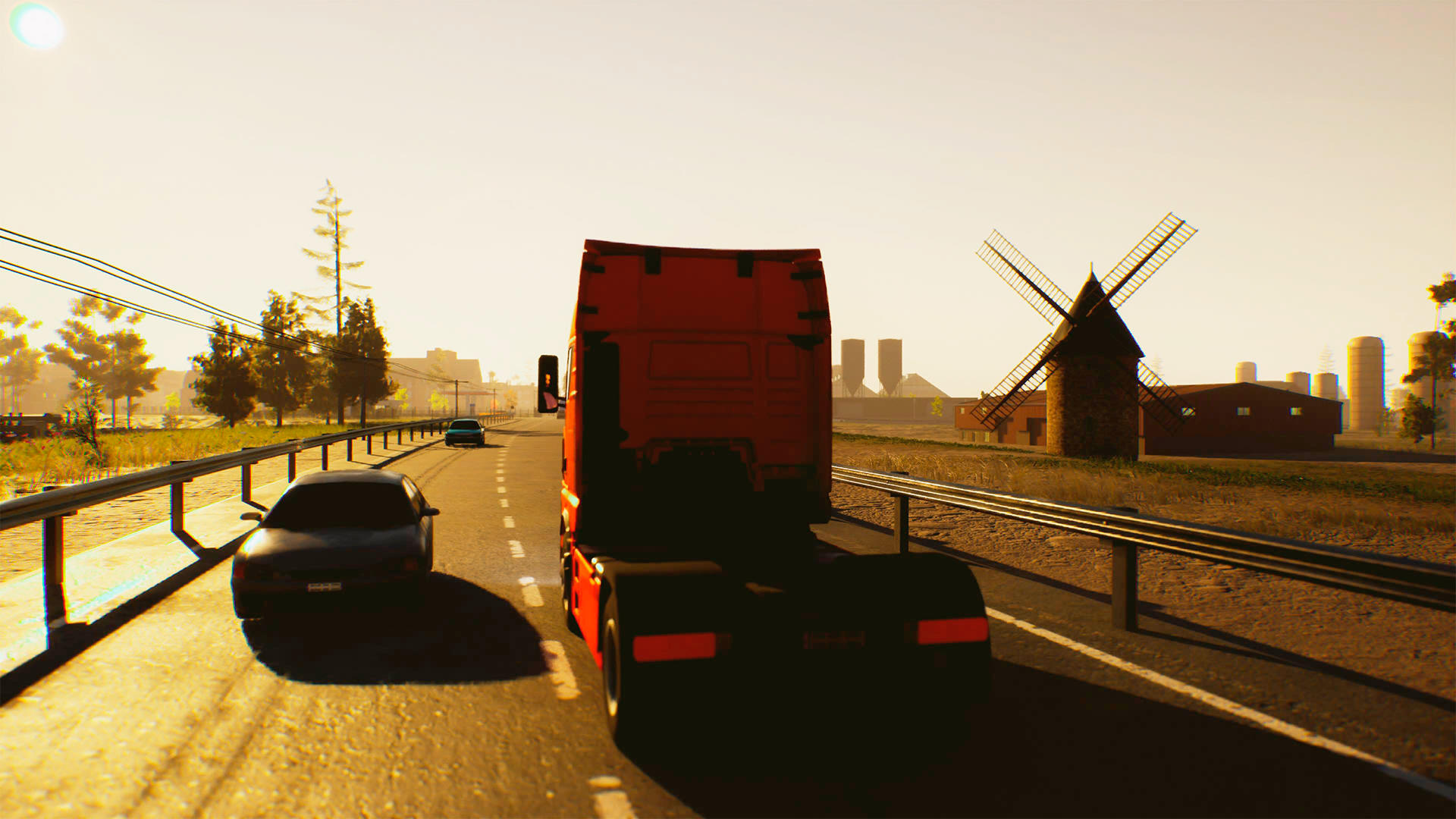 Ein roter LKW fährt auf einer Straße. Ein schwarzes Auto ist vorne. Eine Windmühle und Gebäude sind im Hintergrund.