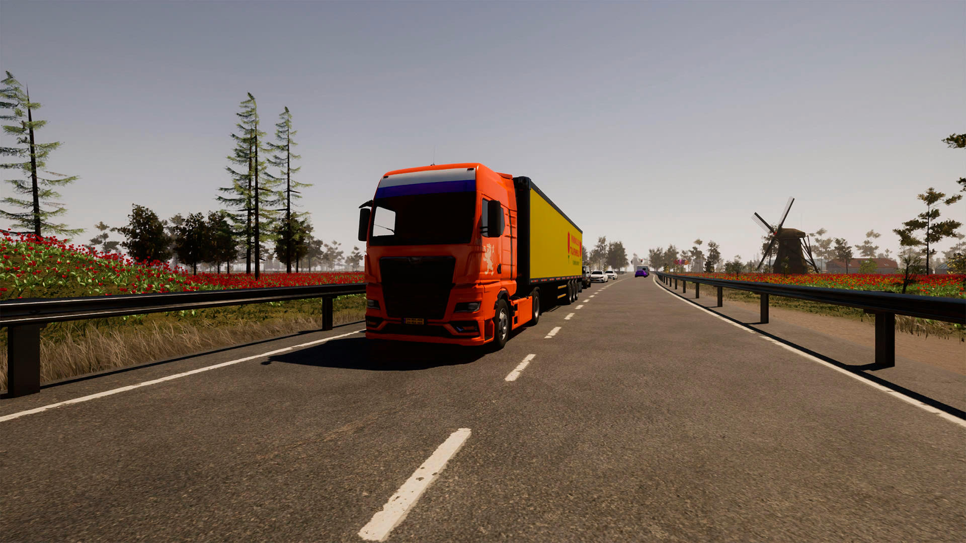 Ein orangefarbener Lastwagen mit gelbem Anhänger fährt auf einer Autobahn. Im Hintergrund sind eine Windmühle und Bäume zu sehen.