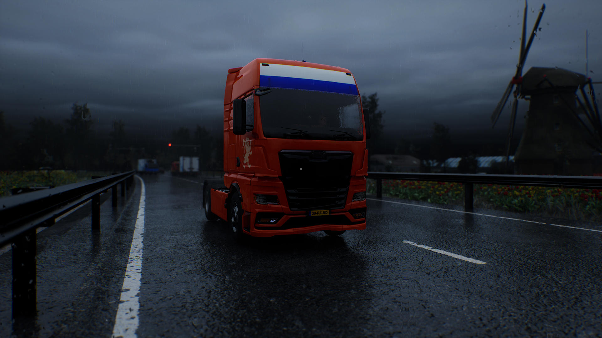 Ein orangefarbener Lastwagen mit niederländischer Flagge fährt auf einer nassen Straße. Eine Windmühle und dunkler Himmel im Hintergrund.