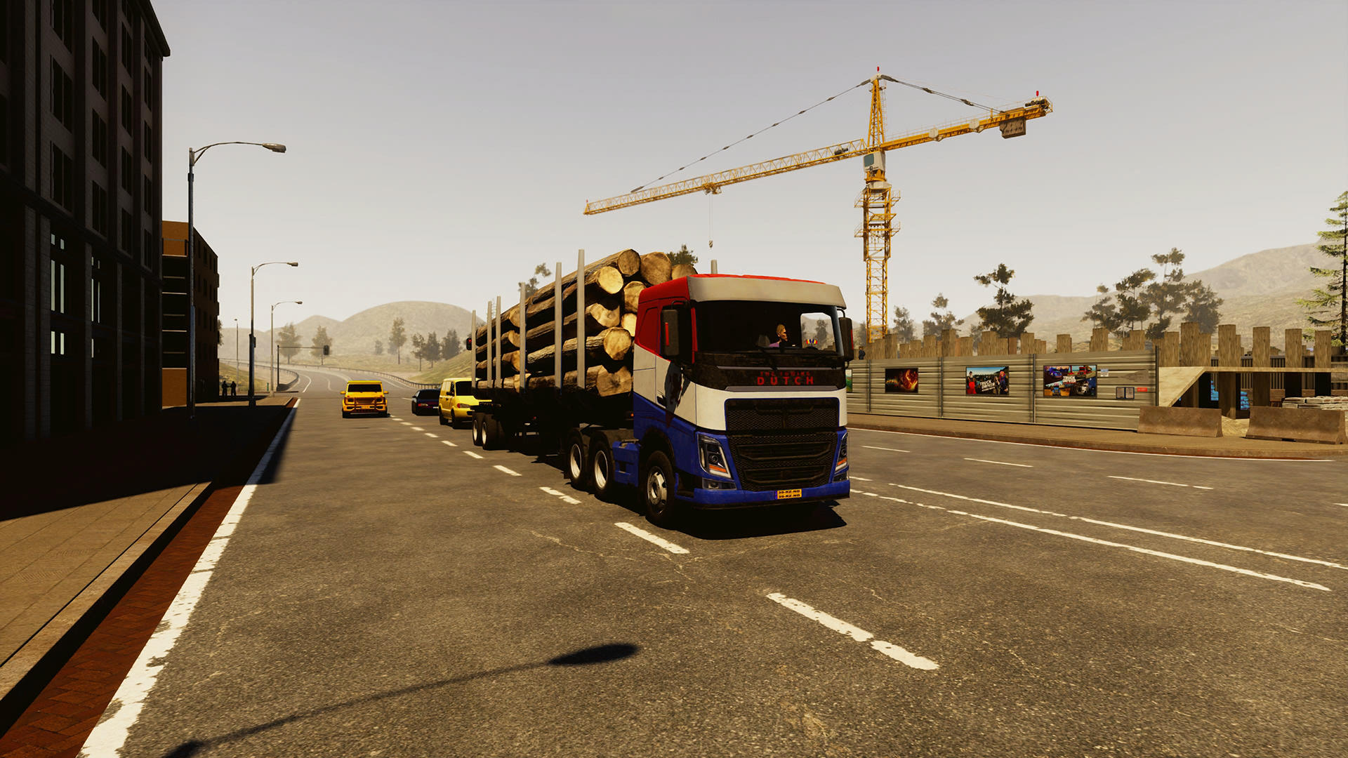 Ein Lkw mit Baumstämmen fährt auf einer Straße. Es gibt andere Fahrzeuge und eine Baustelle. Im Hintergrund ist ein Kran zu sehen.