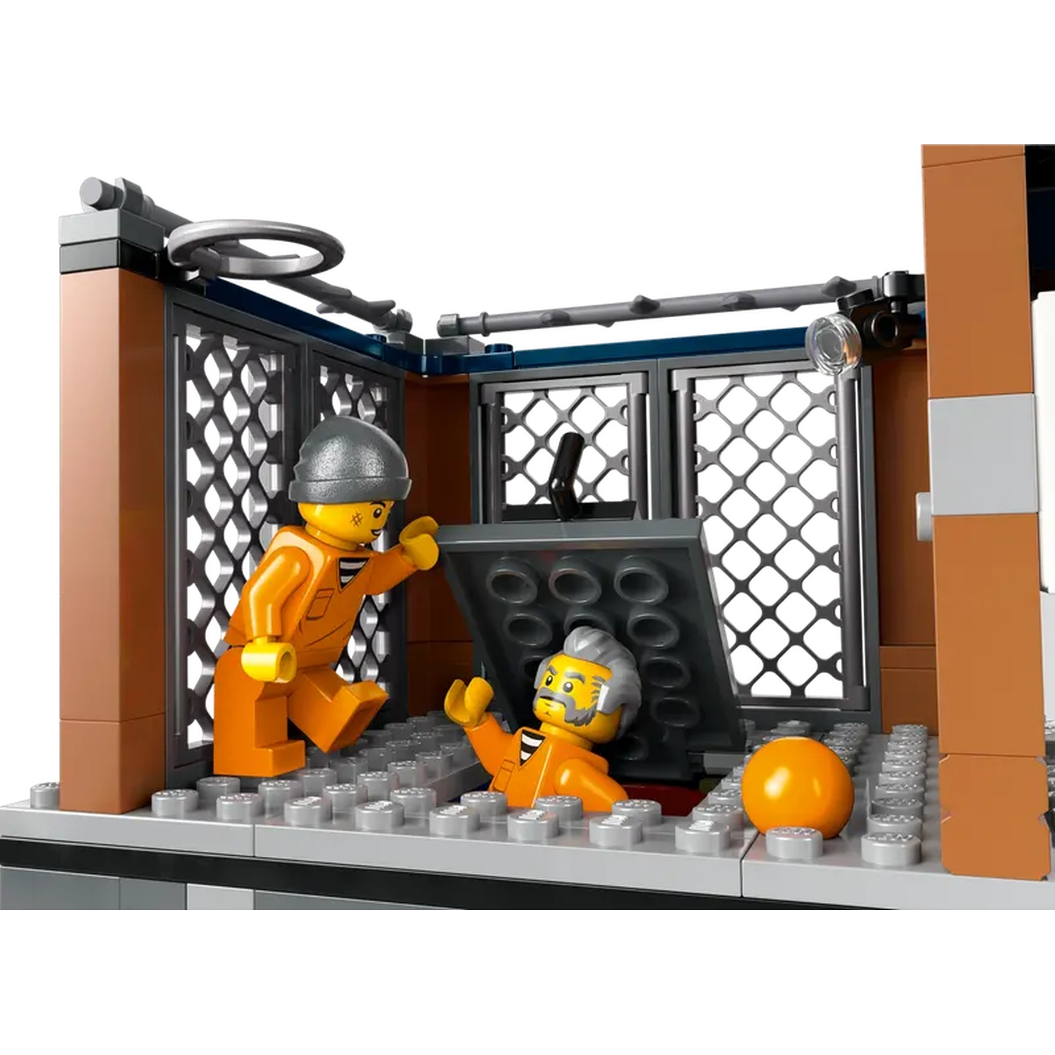 Scène Lego : Deux personnages en combinaisons orange, l'un ouvre une trappe. Un panier de basket est visible. La scène est une cellule.