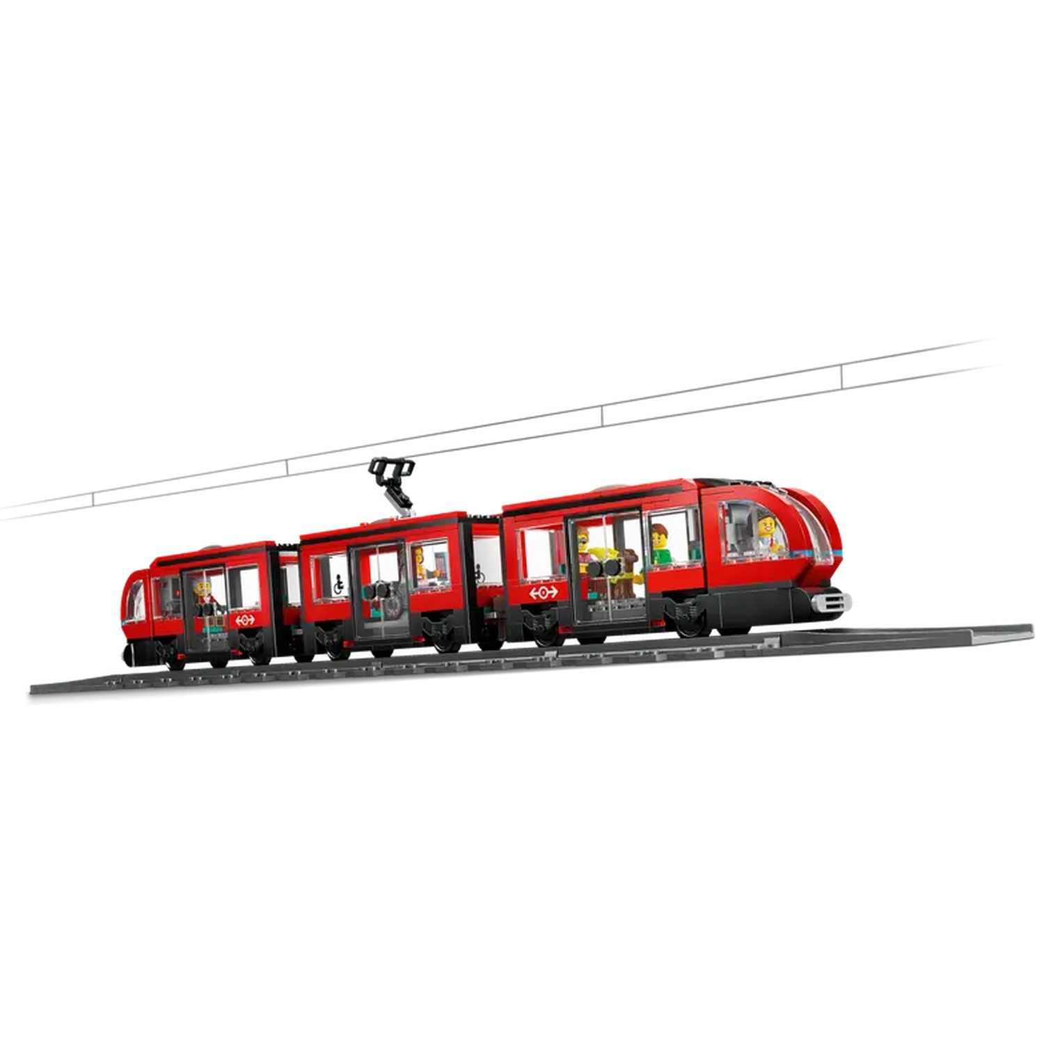 A red toy train on tracks. The train has multiple cars with small figures inside. Wires run above the train.