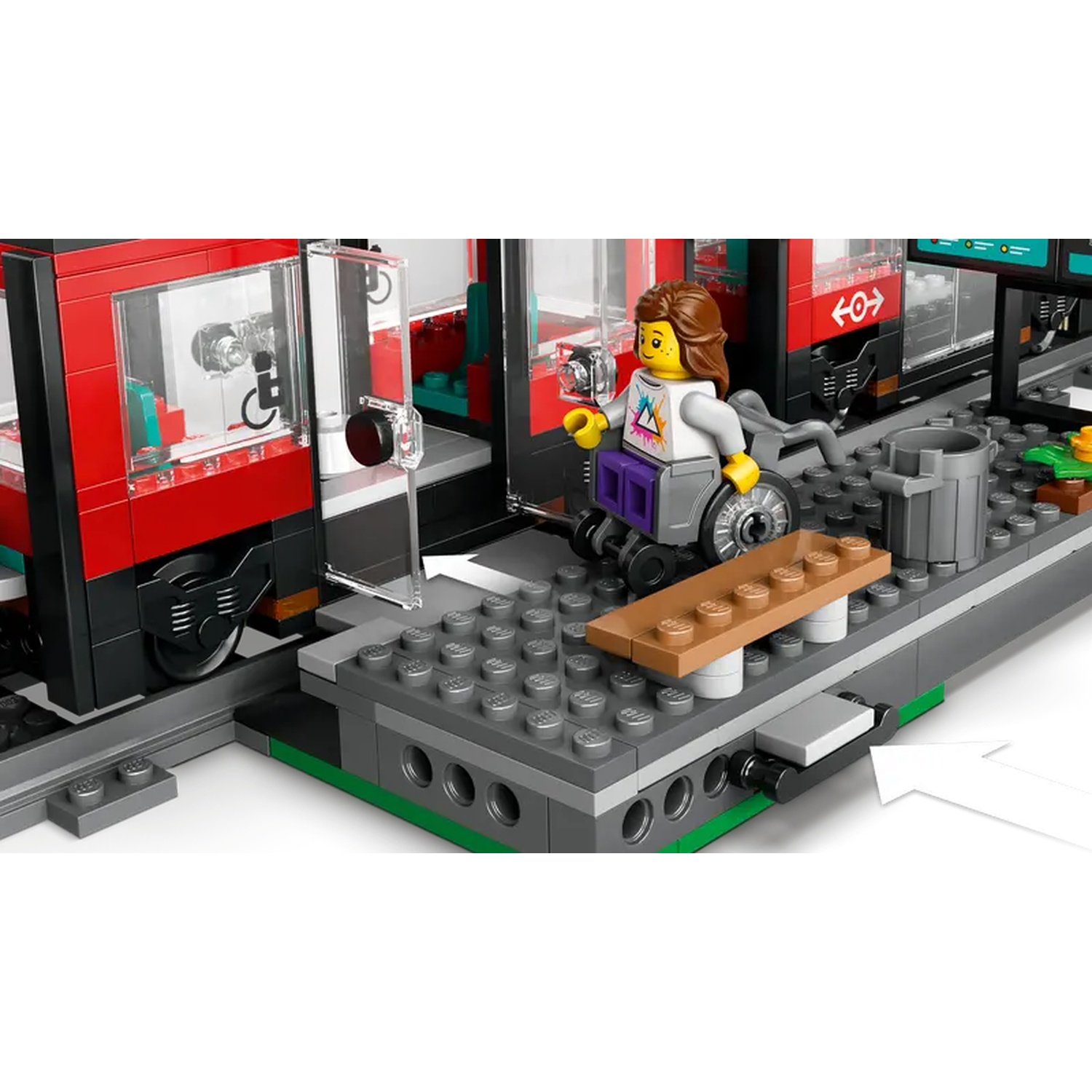 A Lego scene at a train station. A figure in a wheelchair is next to a train. The train is red. There is a trash can.