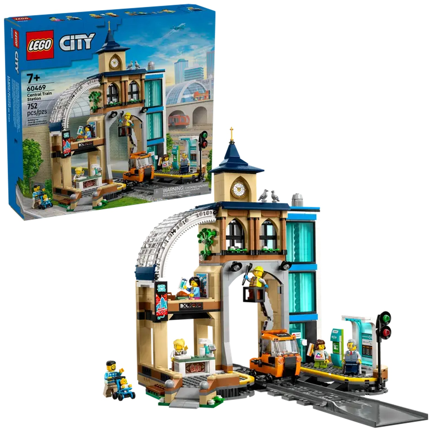 Lego City Central Train Station-set. Bevat gebouwen, figuren, een oranje voertuig en spoorrails. Er staat een doos in de hoek.