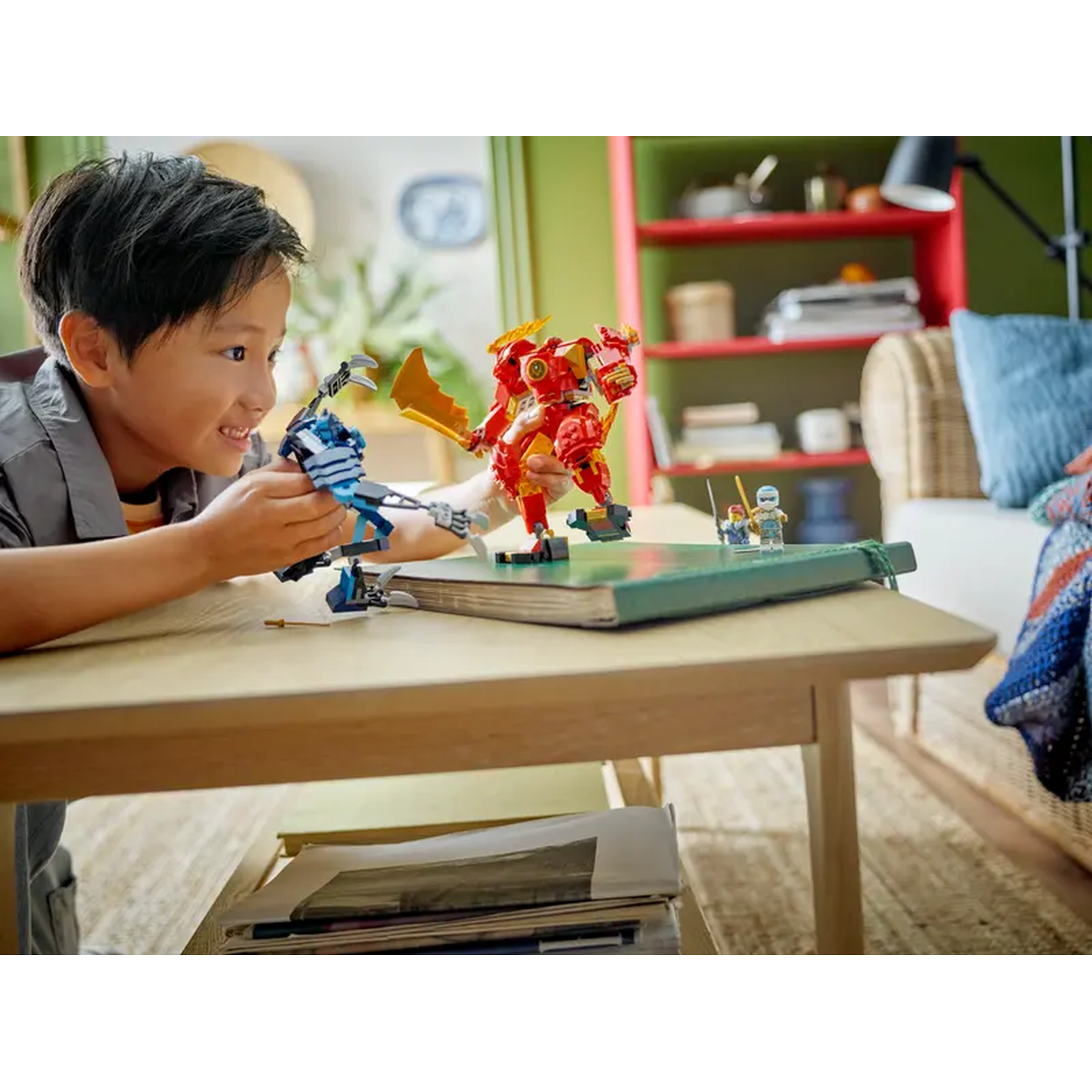 Een jongen glimlacht terwijl hij met LEGO robot speelgoed op een tafel speelt. Een rode robot en een blauwe robot zijn zichtbaar.