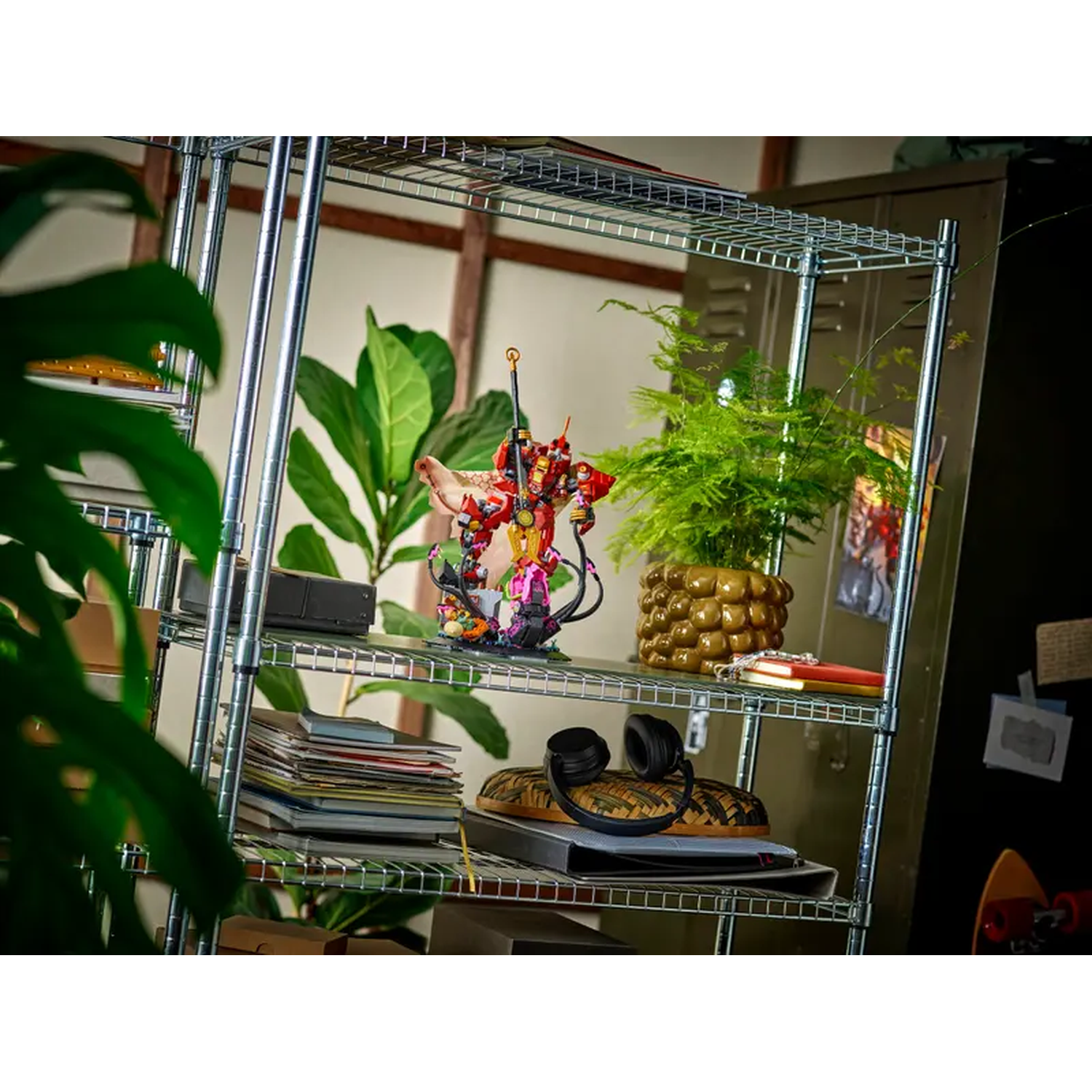 A metal shelf with plants and a figurine. Headphones and books are on the shelf. A skateboard is in the background.