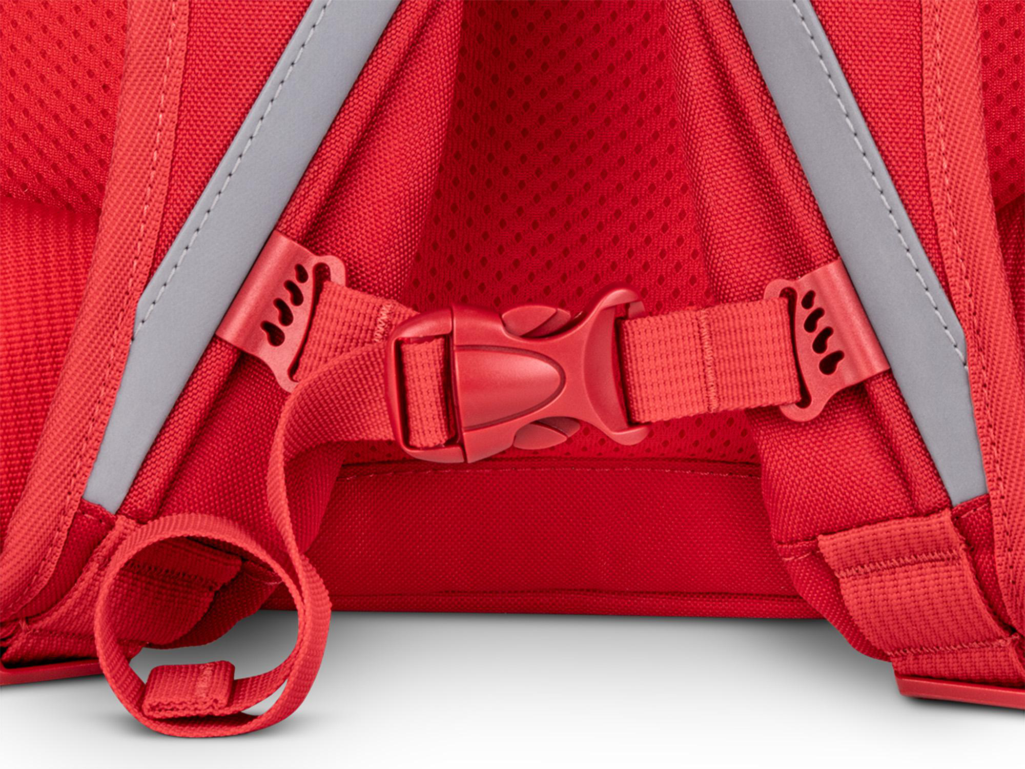 Nahaufnahme der Rückseite eines roten Rucksacks. Sichtbar sind Riemen, Schnallen und reflektierende graue Streifen. Der Fokus liegt auf dem Verschlussmechanismus.