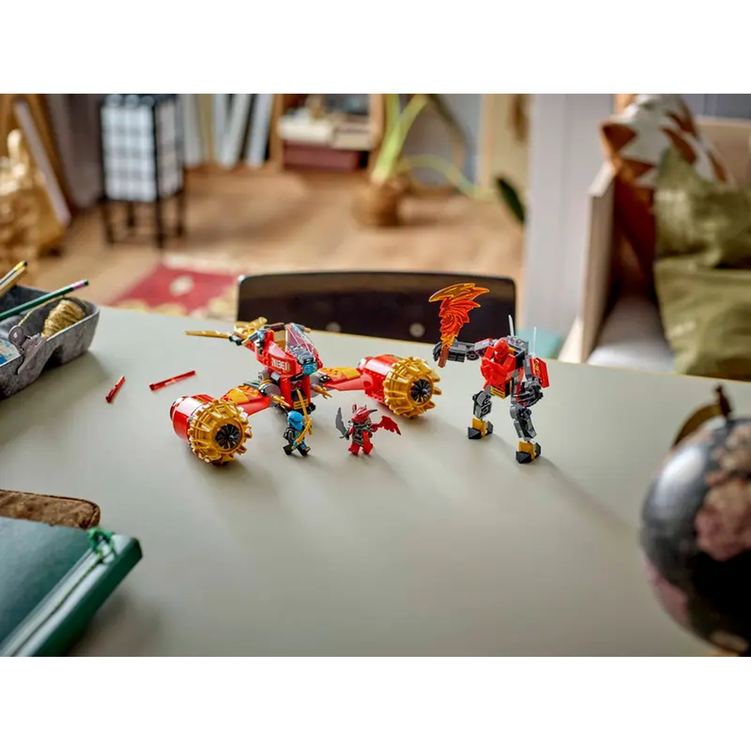 A Lego set featuring a red and gold vehicle, two figures, and a robot with a flame weapon, on a grey table.