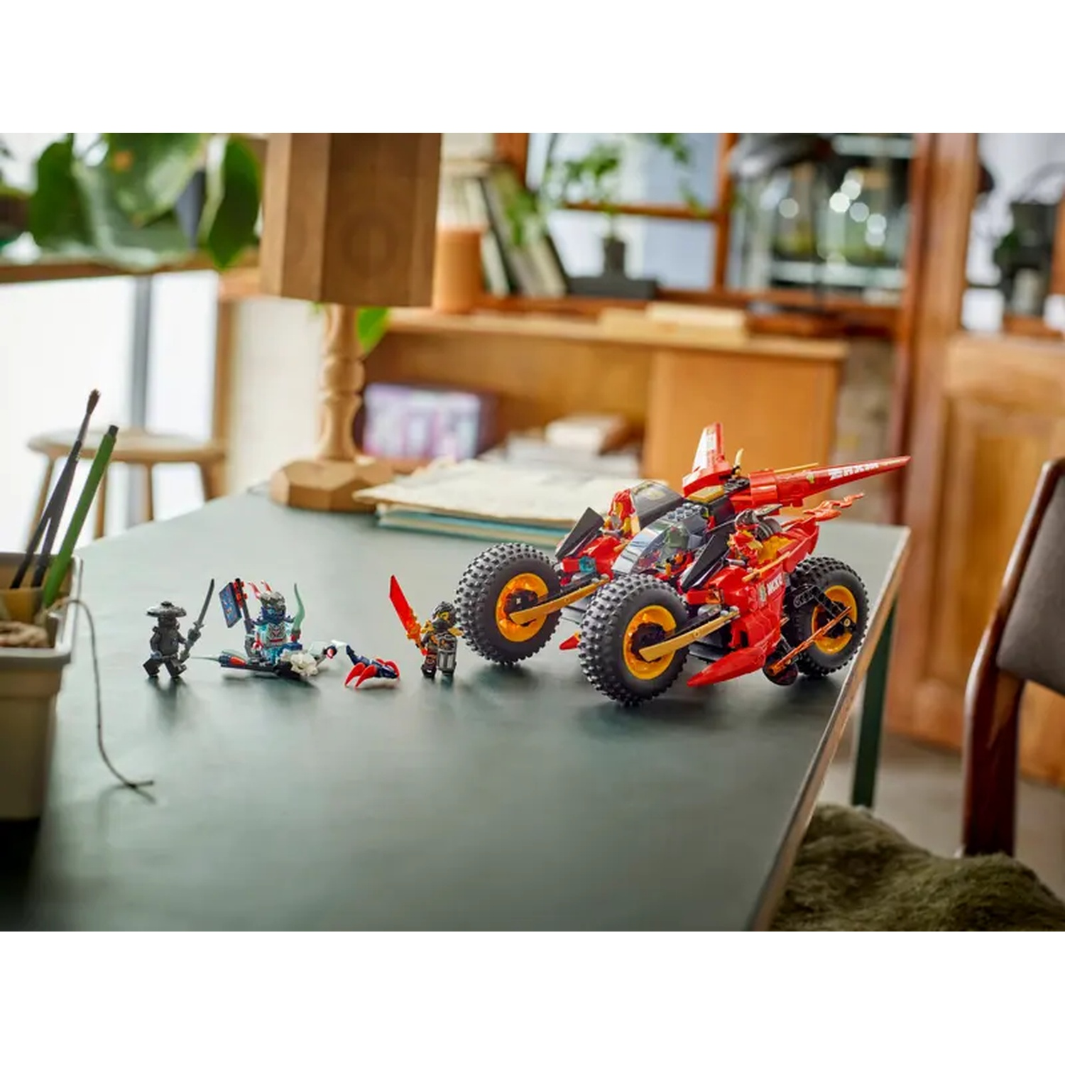 A Lego set on a table. It includes a red and black car, ninja figures, and other Lego pieces against a blurred backdrop.