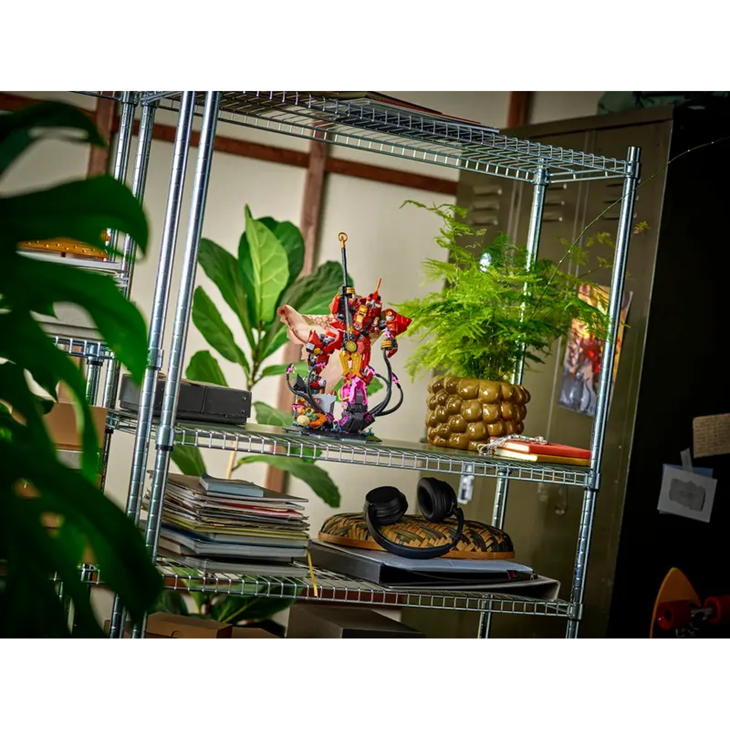 A metal shelf with various items: a plant, a figurine, headphones, books, and a skateboard. The background is a cabinet and a plant.
