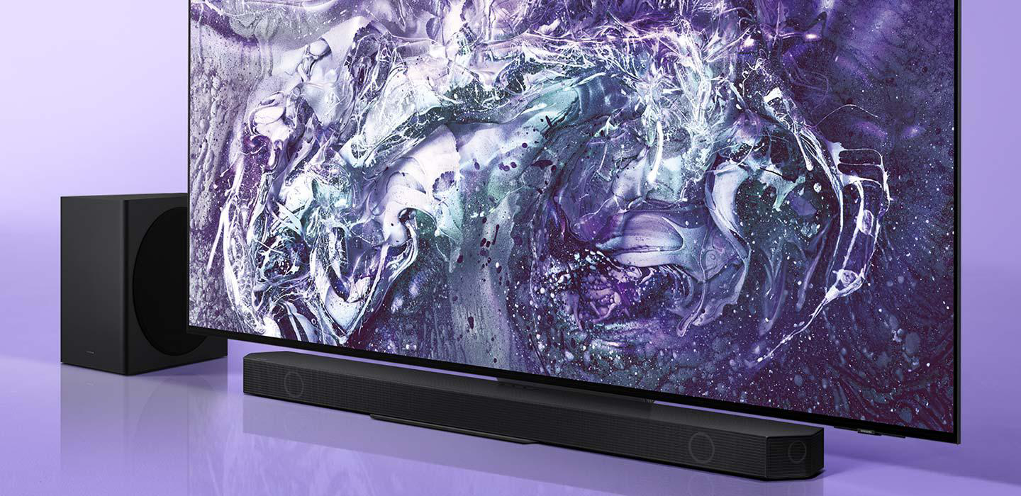 Ein Fernseher mit abstrakter Kunst auf dem Bildschirm steht über einer Soundbar. Links ist ein Subwoofer. Der Hintergrund ist lila.