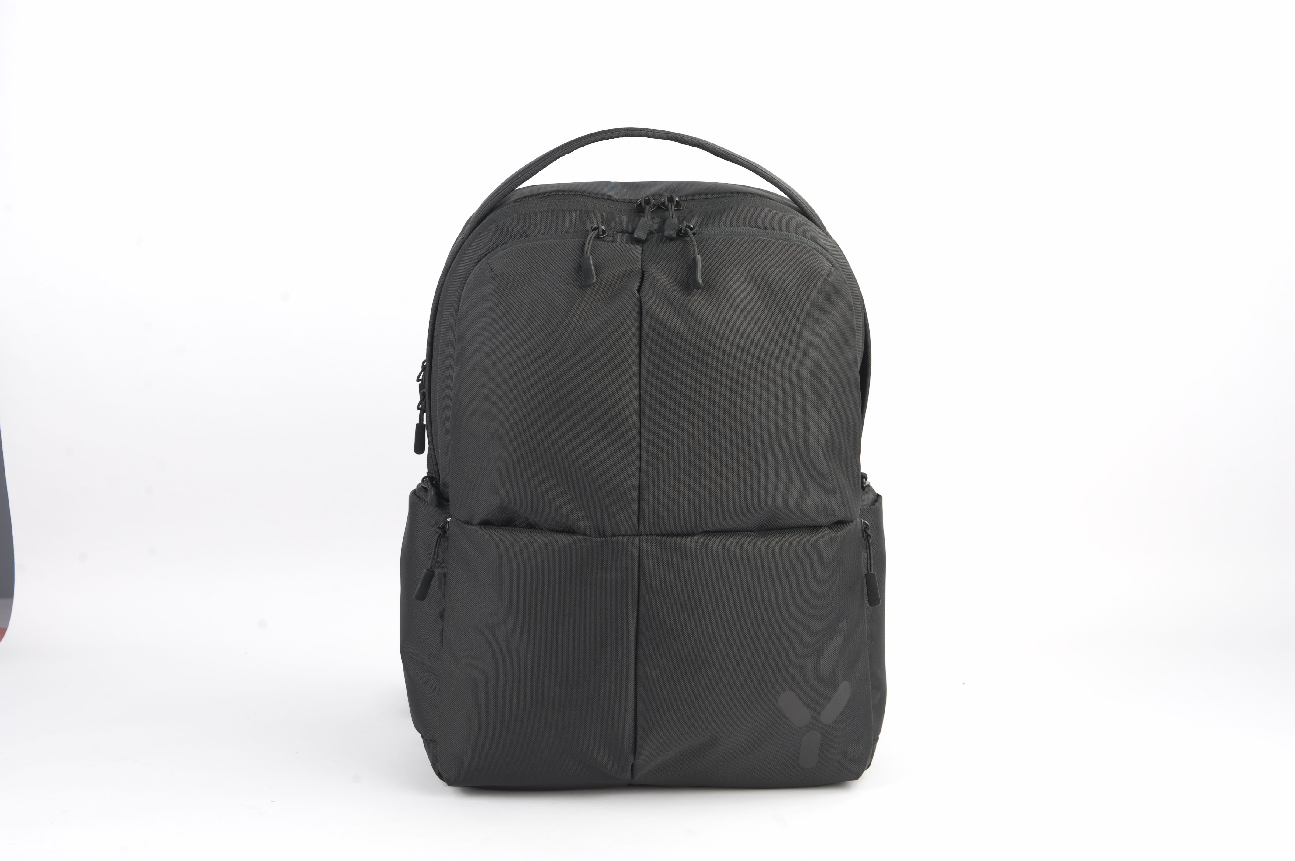 Czarny plecak na białym tle. Ma wiele zamków błyskawicznych i uchwyt na górze.