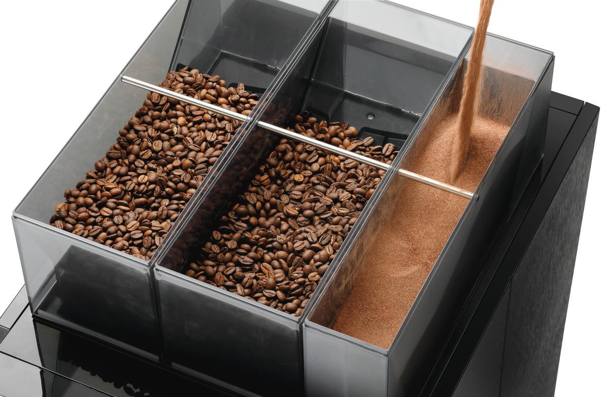 Kaffeebohnen und gemahlener Kaffee in einem transparenten Spender. Ein Strom gemahlenen Kaffees fließt in das dritte Fach.