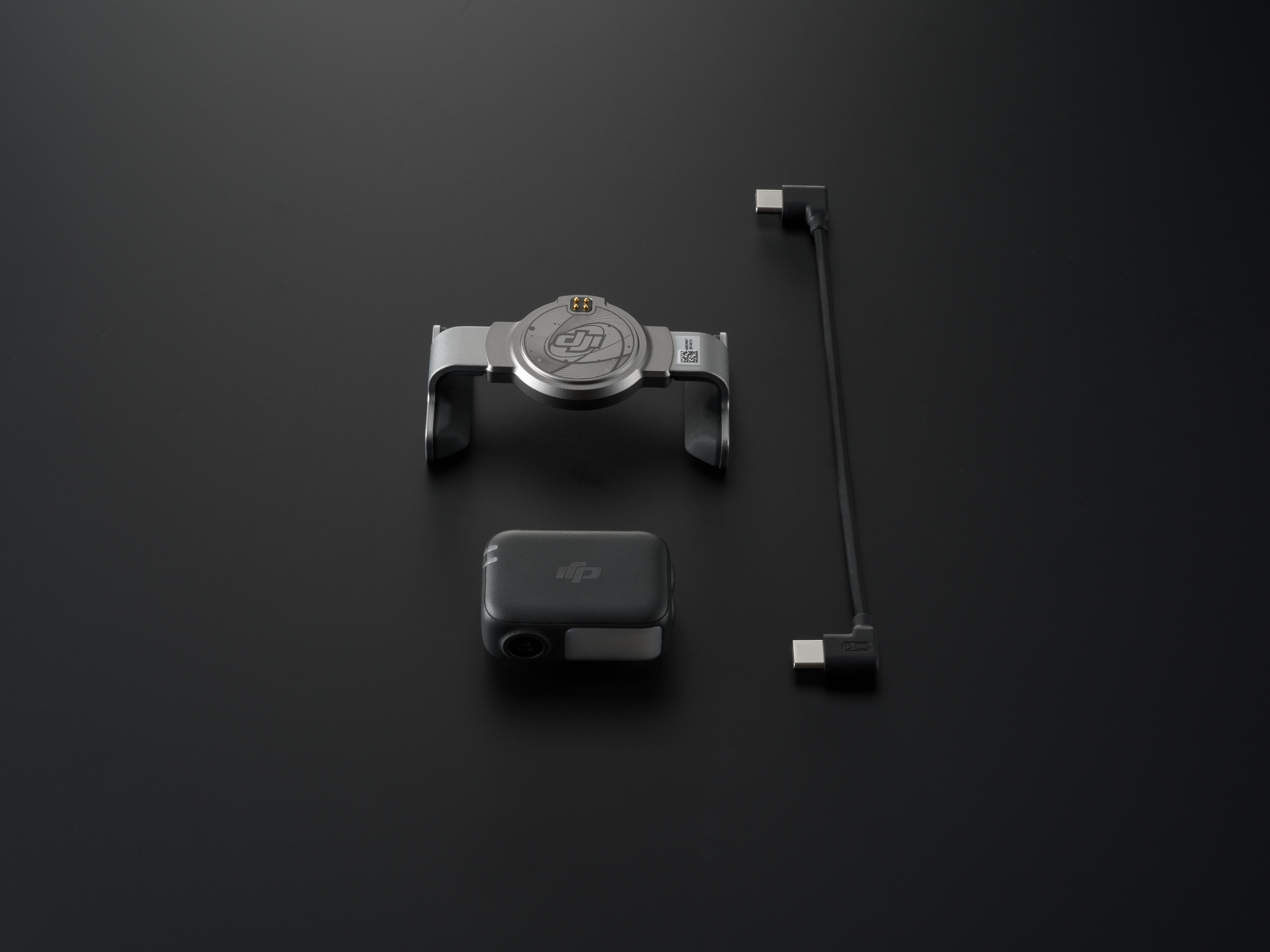 DJI Osmo Action Kamera-Kit auf schwarzer Oberfläche. Enthält Kamera, Halterung, Kabel und Ladestation.