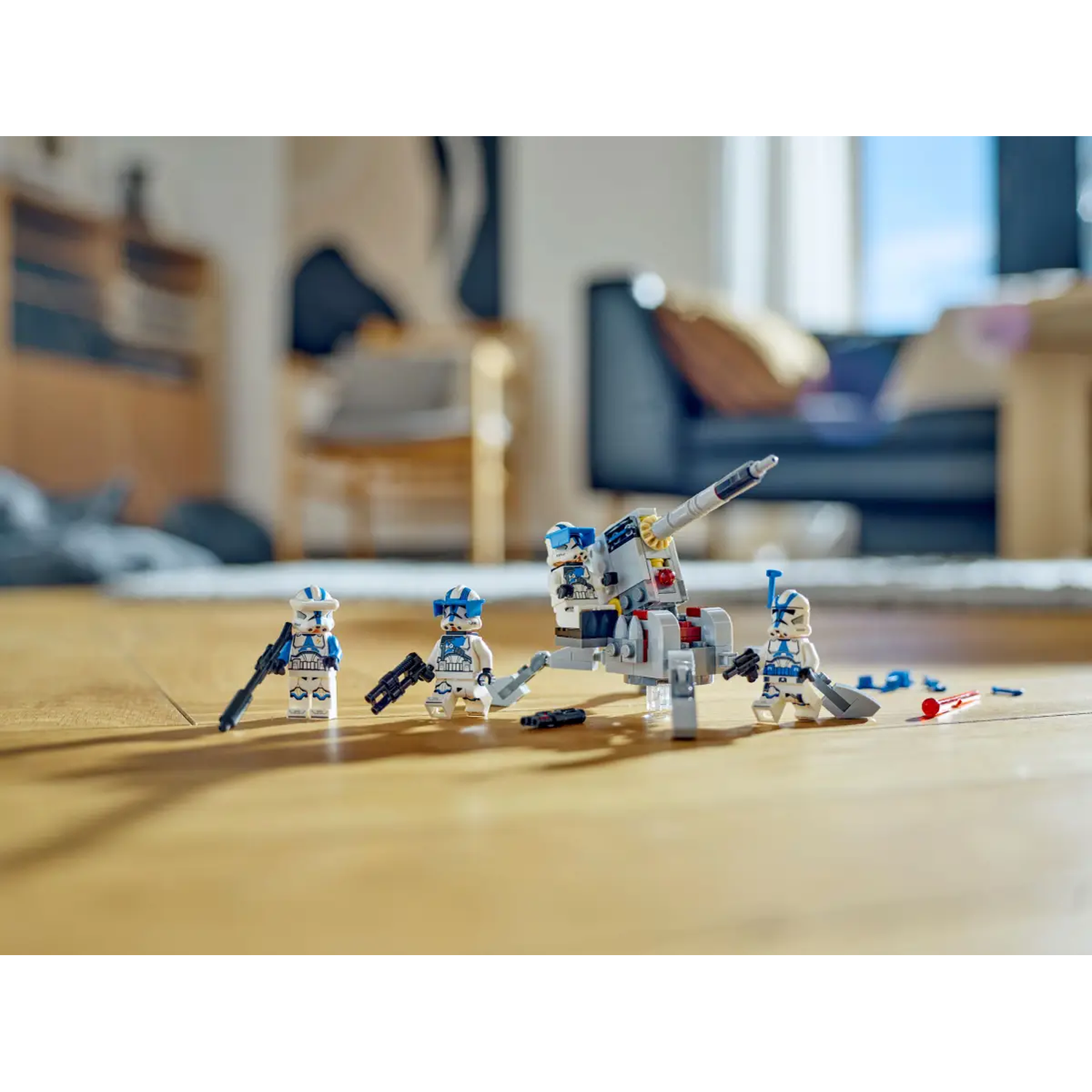 Lego Star Wars set on a wooden floor. Features clone troopers with blasters and a cannon. Background is blurred interior.