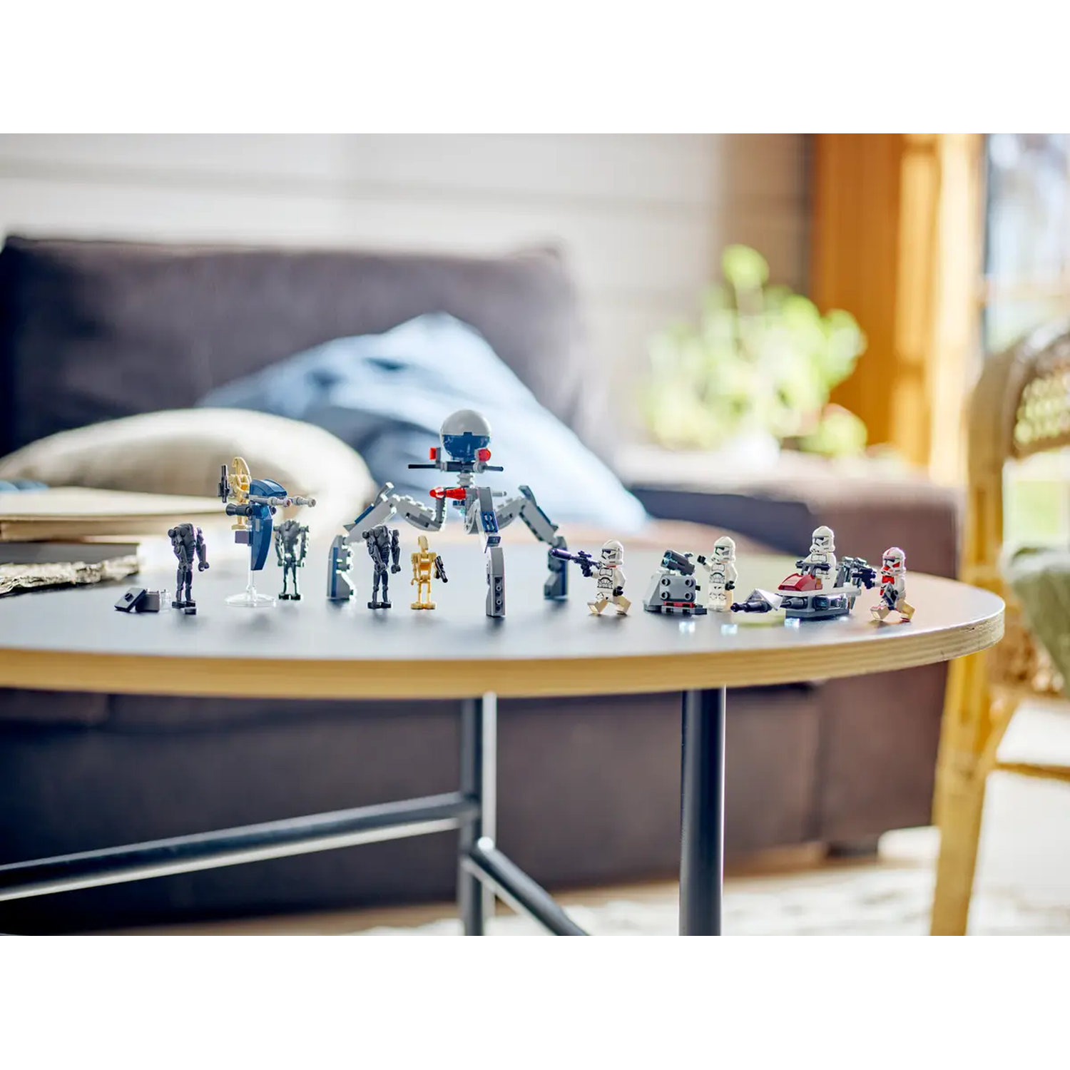Lego Star Wars set on a table. Includes various minifigures, a droid, and a speeder. Background has a couch and window.
