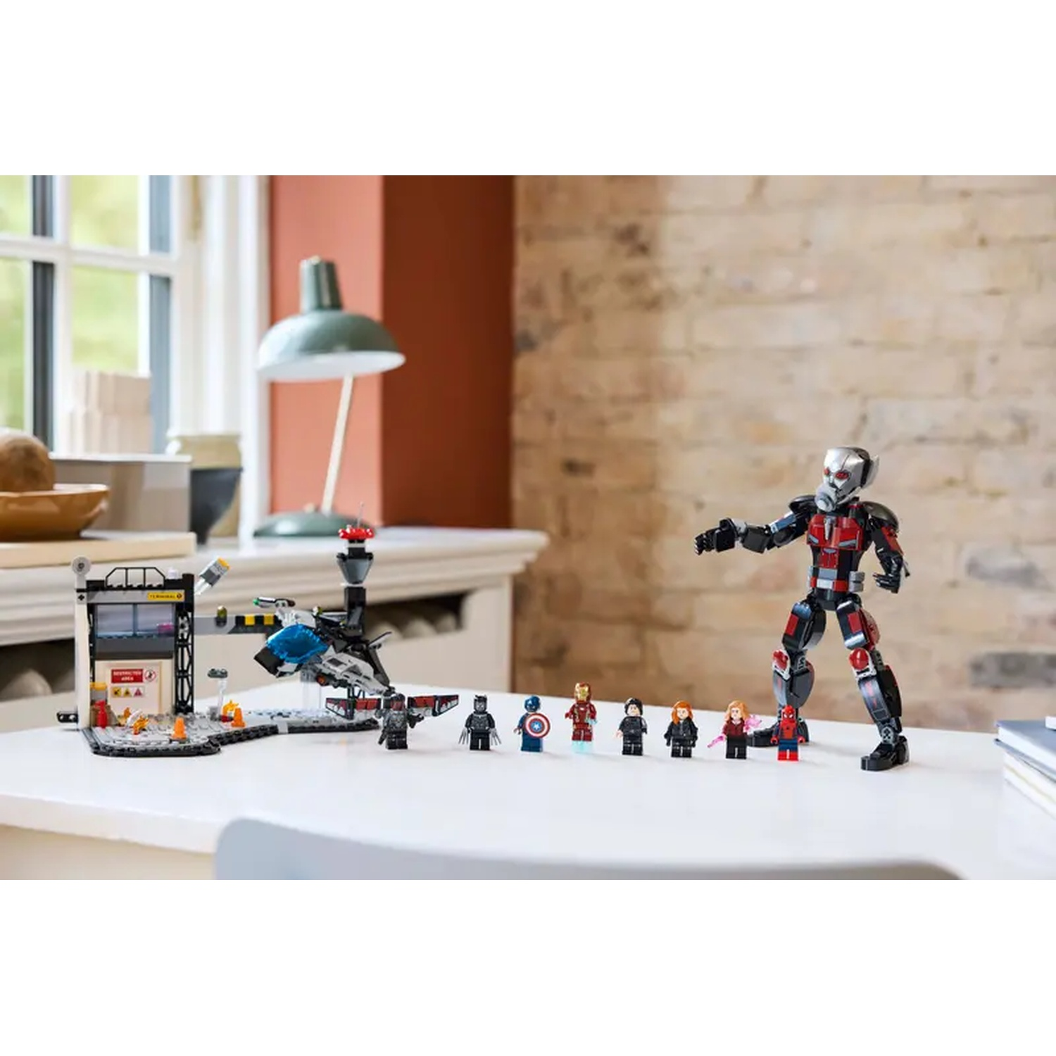 Lego set with Ant-Man figure and other Marvel characters on a white table. Includes a building and a jet.