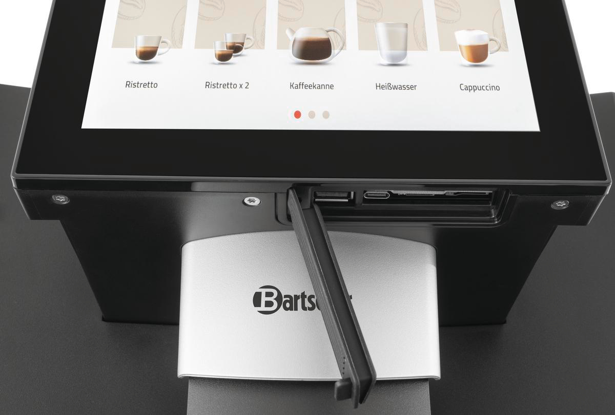 Kaffeemaschinen-Display mit Kaffeeoptionen. Maschine hat einen silbernen Sockel mit Bartscher-Logo. Ein USB-Anschluss ist sichtbar.