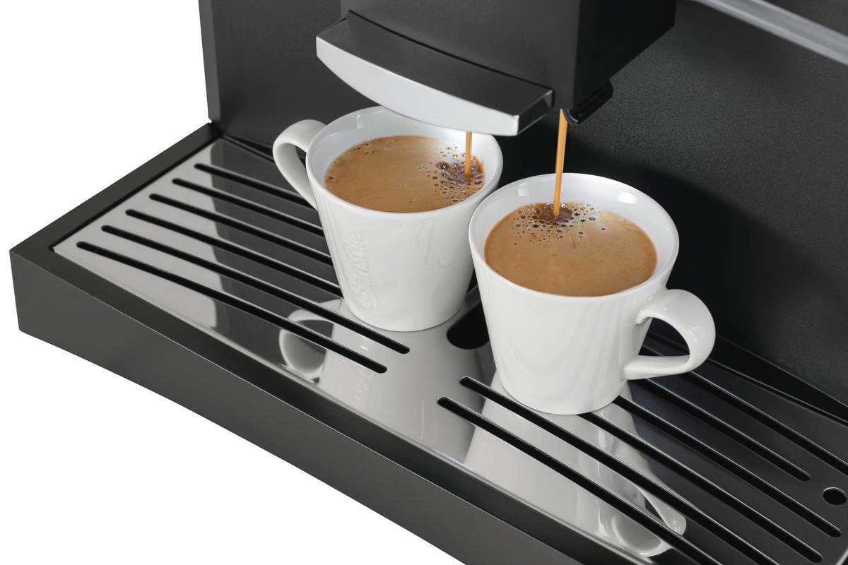 Kaffeemaschine, die Kaffee in zwei weiße Tassen ausgibt. Kaffeeströme sind sichtbar. Die Maschine und die Tassen stehen auf einem Tablett.