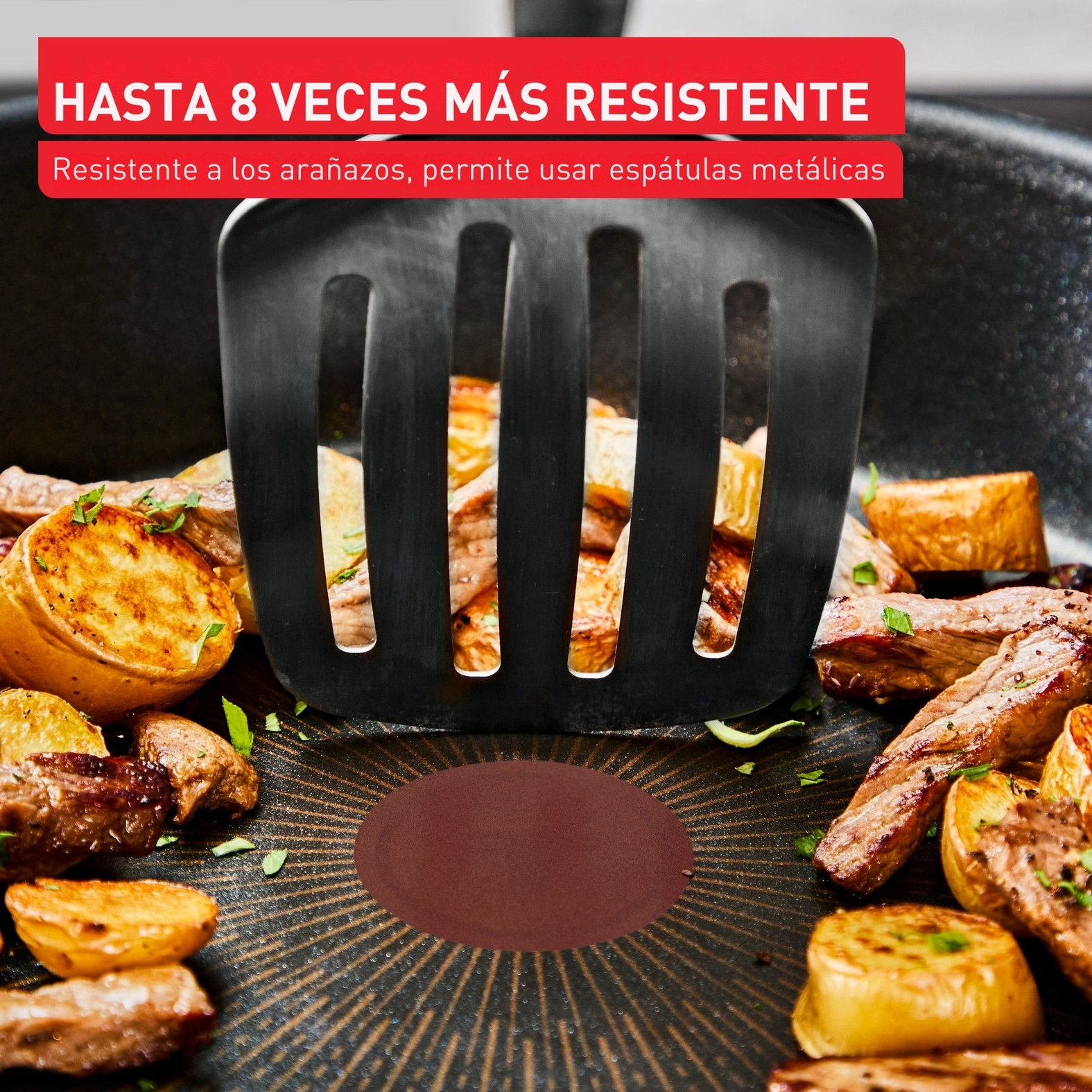 Una espátula negra en una sartén con comida. La sartén contiene patatas y carne cocinadas. Texto rojo arriba: Hasta 8 veces más fuerte.
