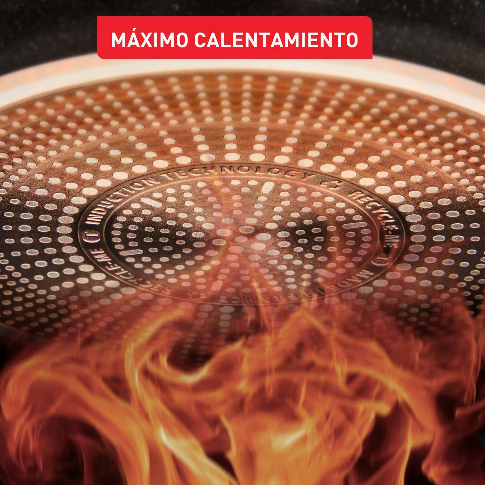 Primer plano de la base de una sartén con texto 'MAXIMO CALENTAMIENTO'. Las llamas suben. La sartén tiene 'INDUCTION TECHNOLOGY'.
