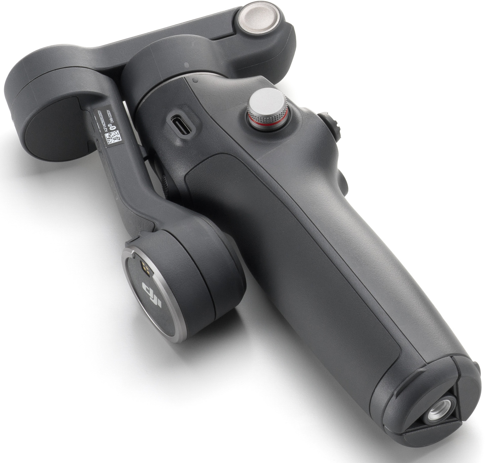 Egy szürke DJI Osmo Mobile gimbal stabilizátor fehér felületen. Gombok és fogantyú van rajta.