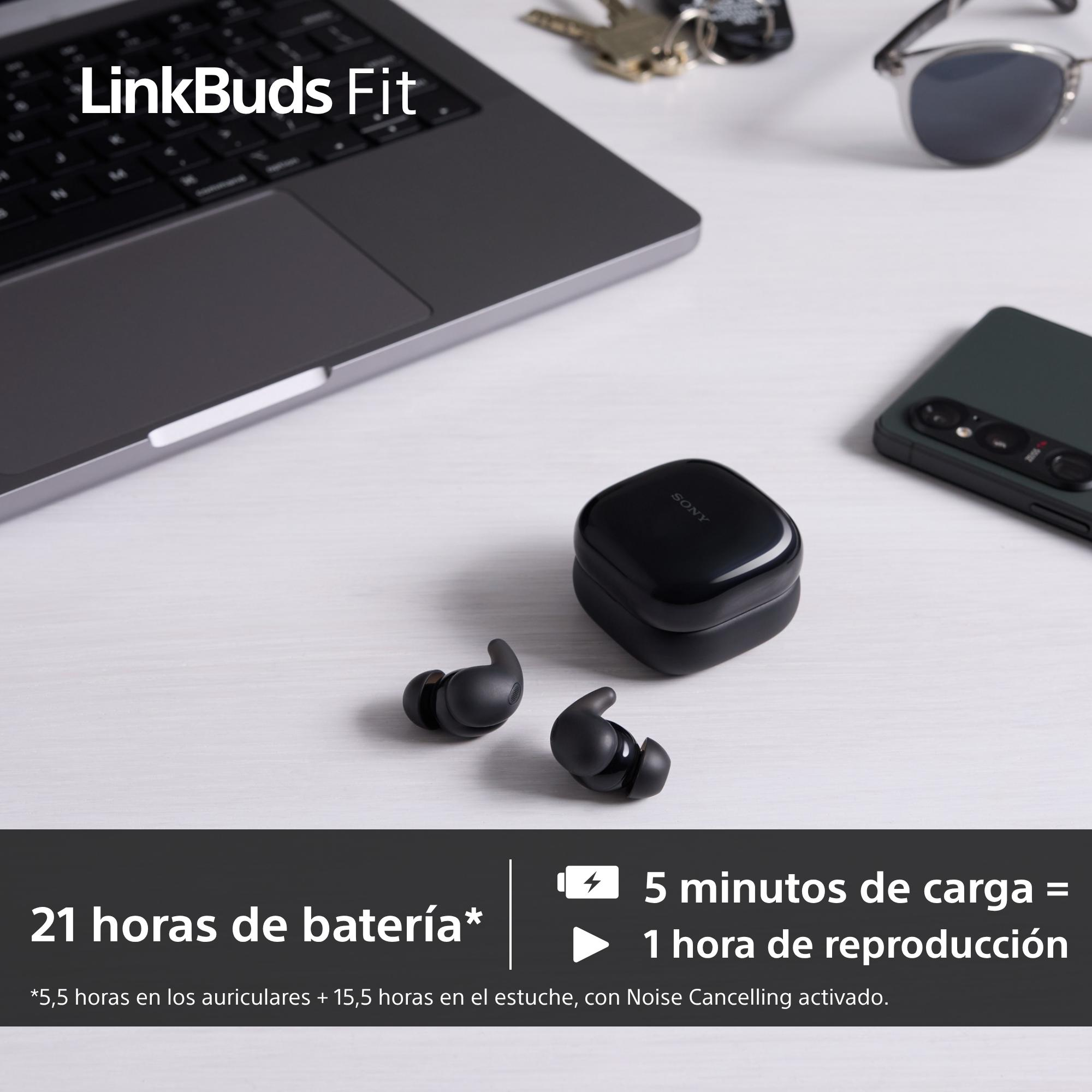Auriculares y estuche de carga Sony negros sobre una superficie blanca con portátil, teléfono y gafas.