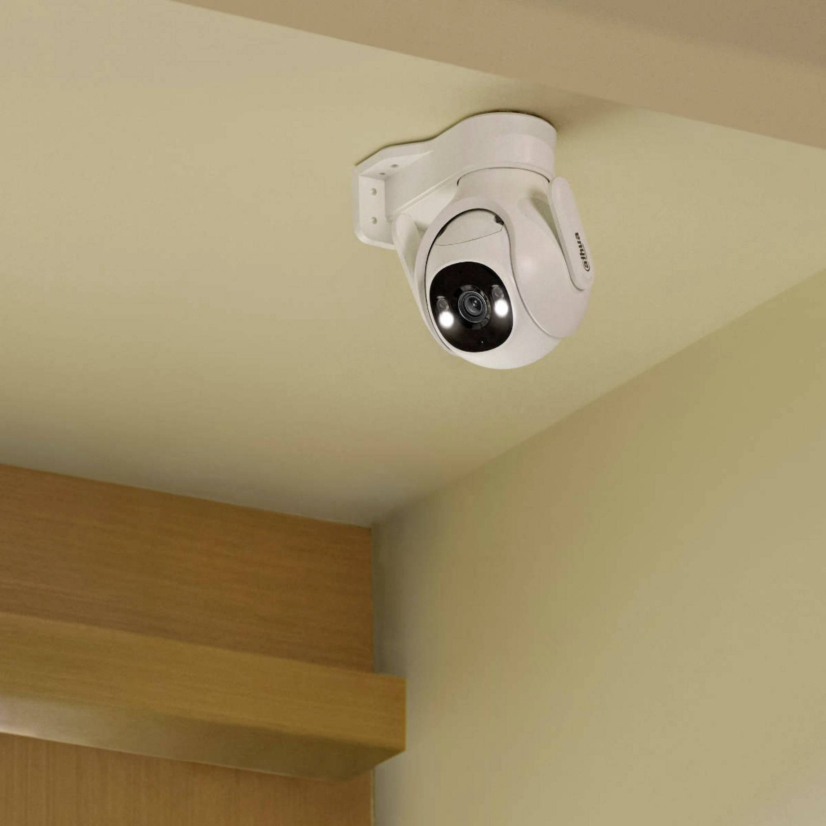 Eine weiße Überwachungskamera an einer beigefarbenen Decke. Die Kamera hat ein dunkles Objektiv und Lichter. Holzverkleidung ist sichtbar.
