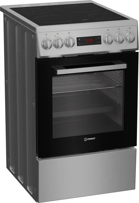Un four Indesit en acier inoxydable. Il a une porte vitrée noire, un affichage numérique et des boutons pour la table de cuisson.