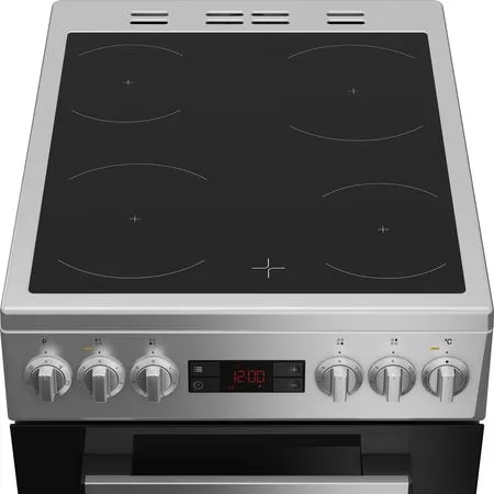 Une cuisinière électrique argentée avec une plaque de cuisson noire, quatre brûleurs, des boutons de commande et une horloge numérique affichant 12:00. En dessous, un four noir.