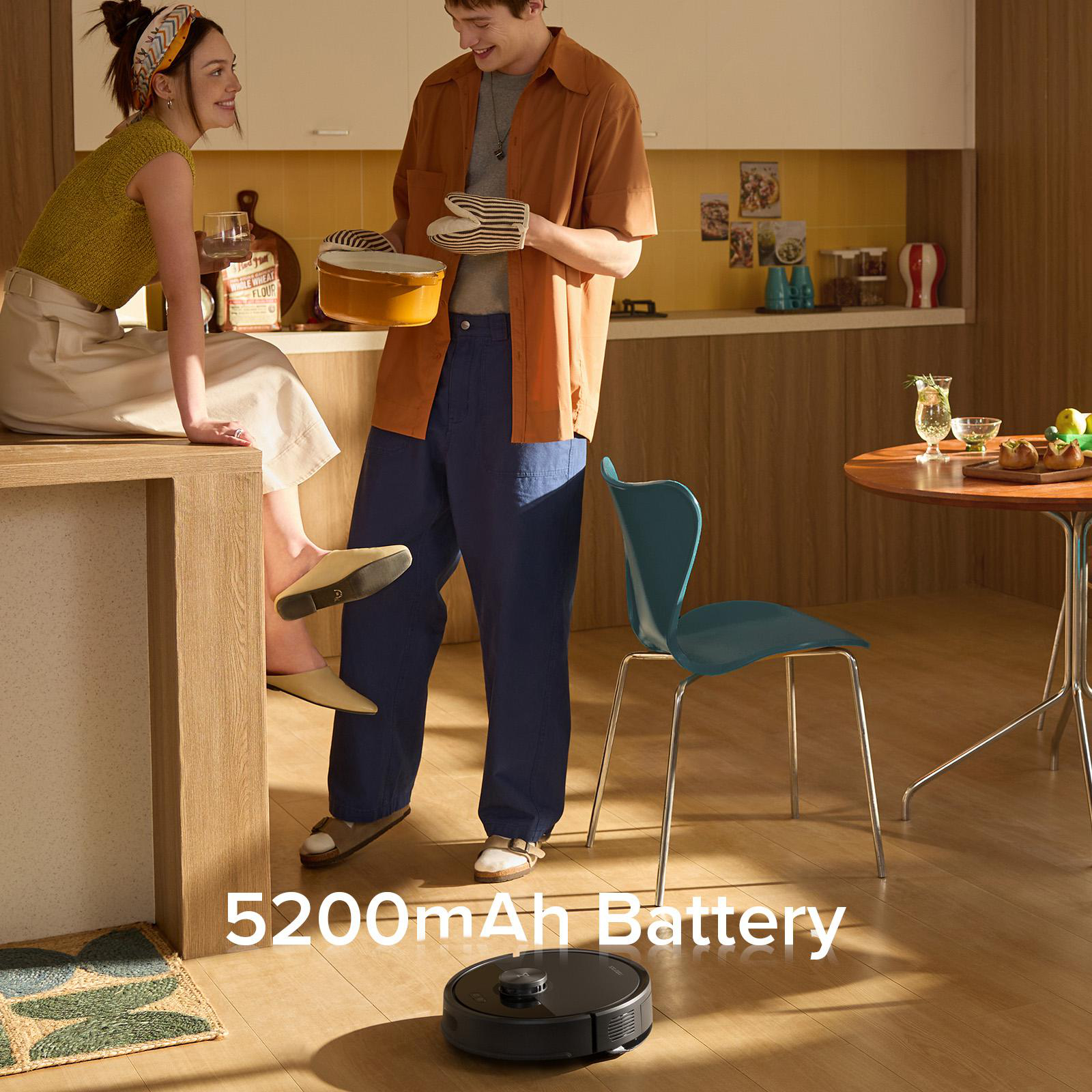 Ein Paar in einer Küche, einer hält einen Topf, ein Roboter-Staubsauger auf dem Boden und ein Text mit 5200mAh Akku.