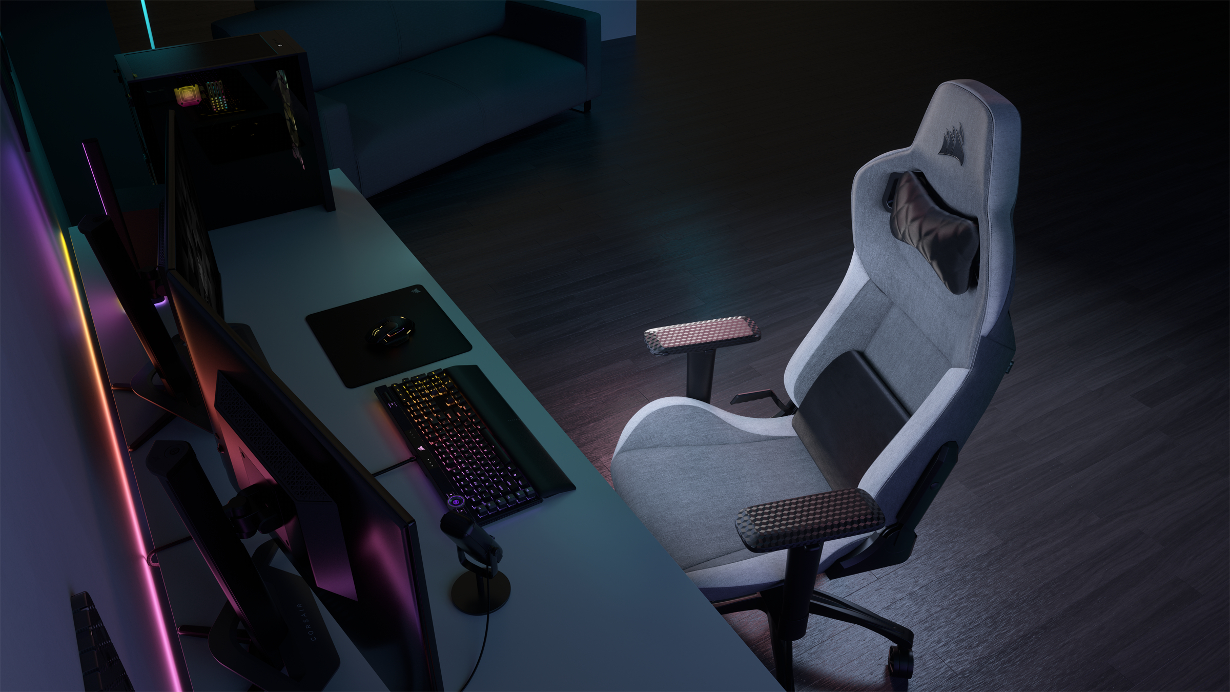 Gaming-Setup mit weißem Stuhl, Schreibtisch, PC und Peripheriegeräten. Der Raum ist schwach beleuchtet.