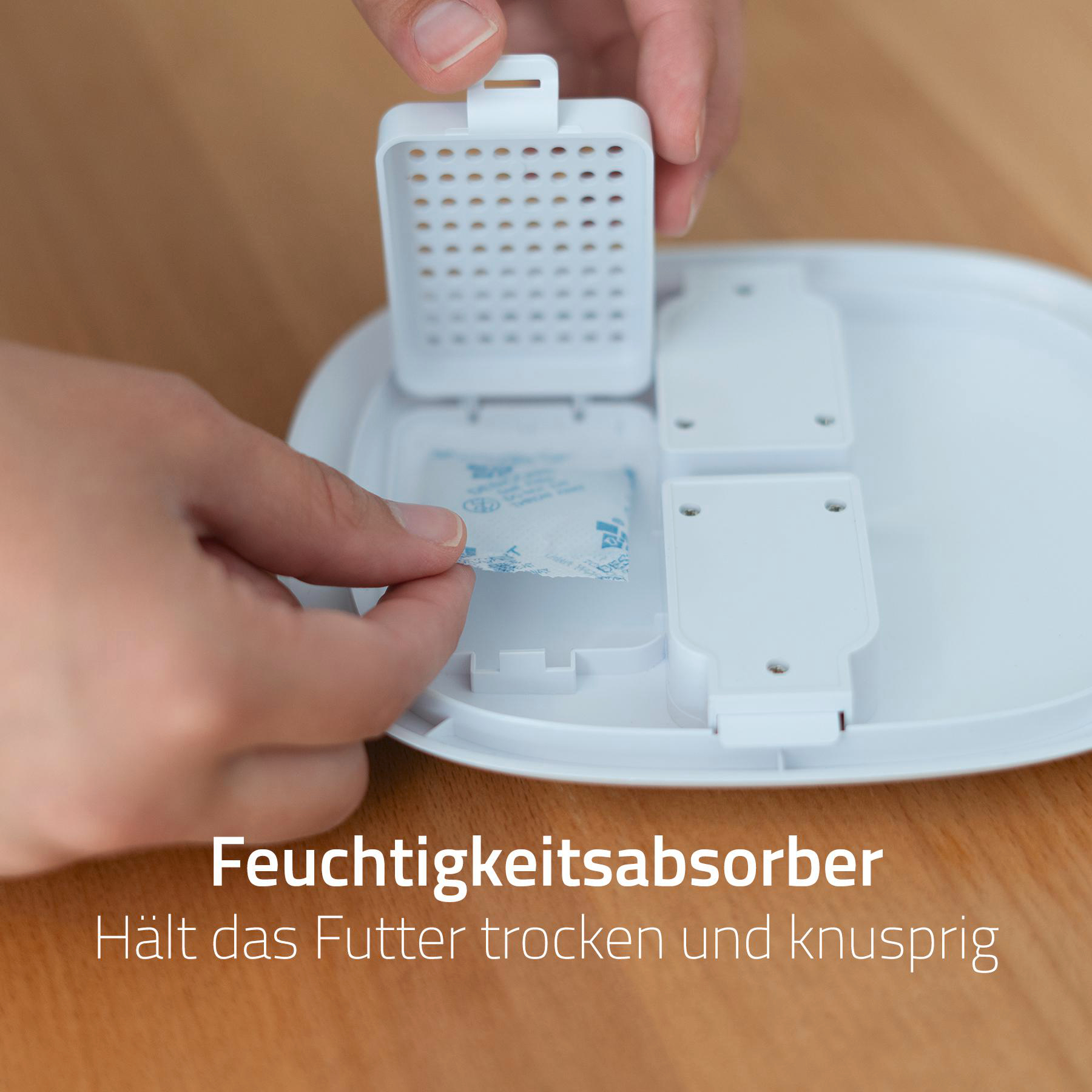 Hände legen ein Trockenmittelpack in einen weißen Feuchtigkeitsabsorberbehälter. Der Behälter ist geöffnet.