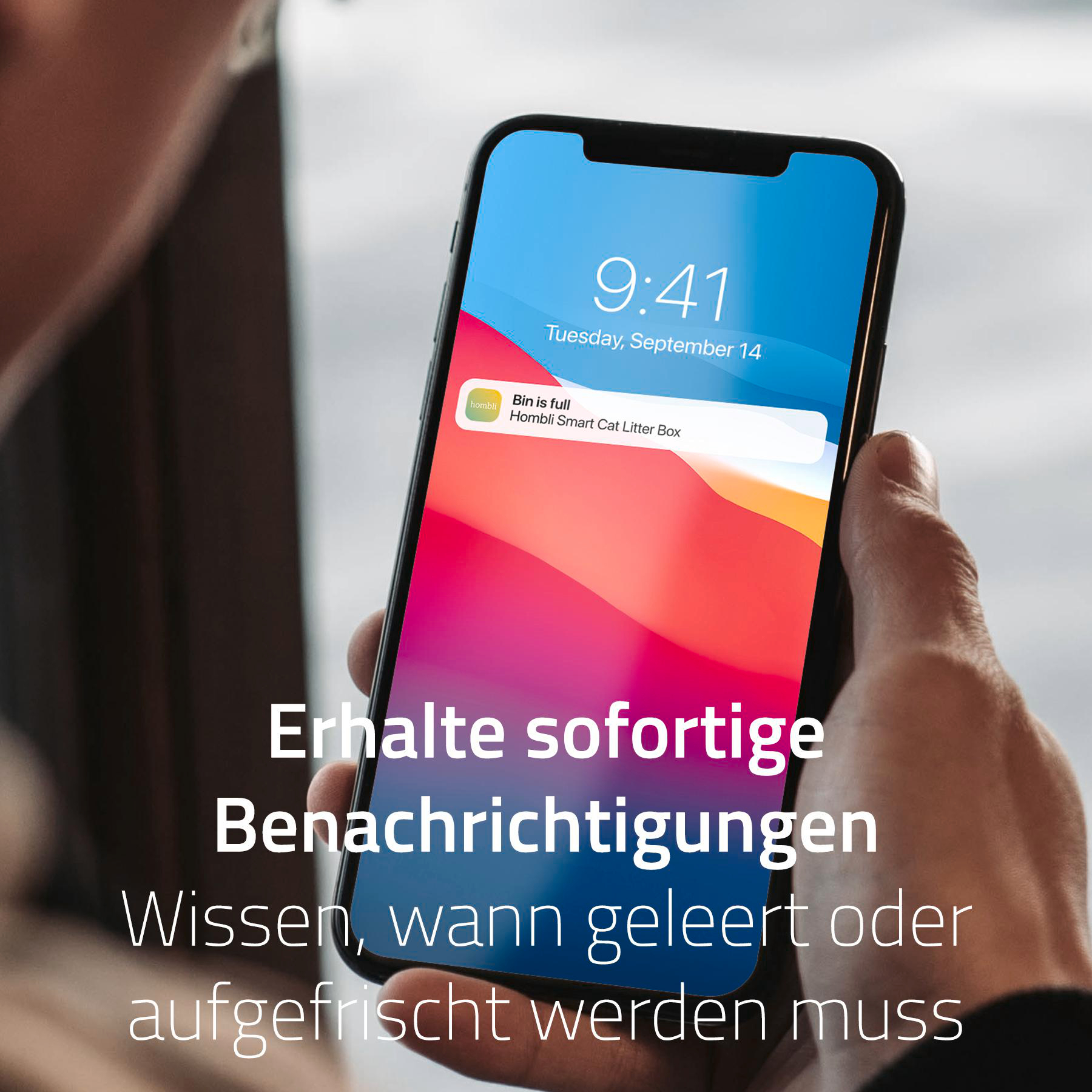 Eine Person hält ein Telefon mit einer Benachrichtigung: Bin is full, von Hombli Smart Cat Litter Box.