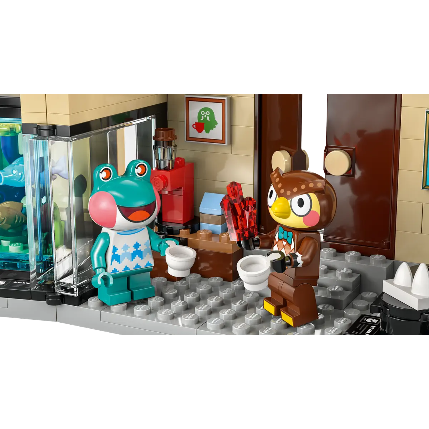 Een Lego-scène toont een kikker en een uil die kopjes vasthouden. Een rode koffiemachine, een foto en een deur staan op de achtergrond.