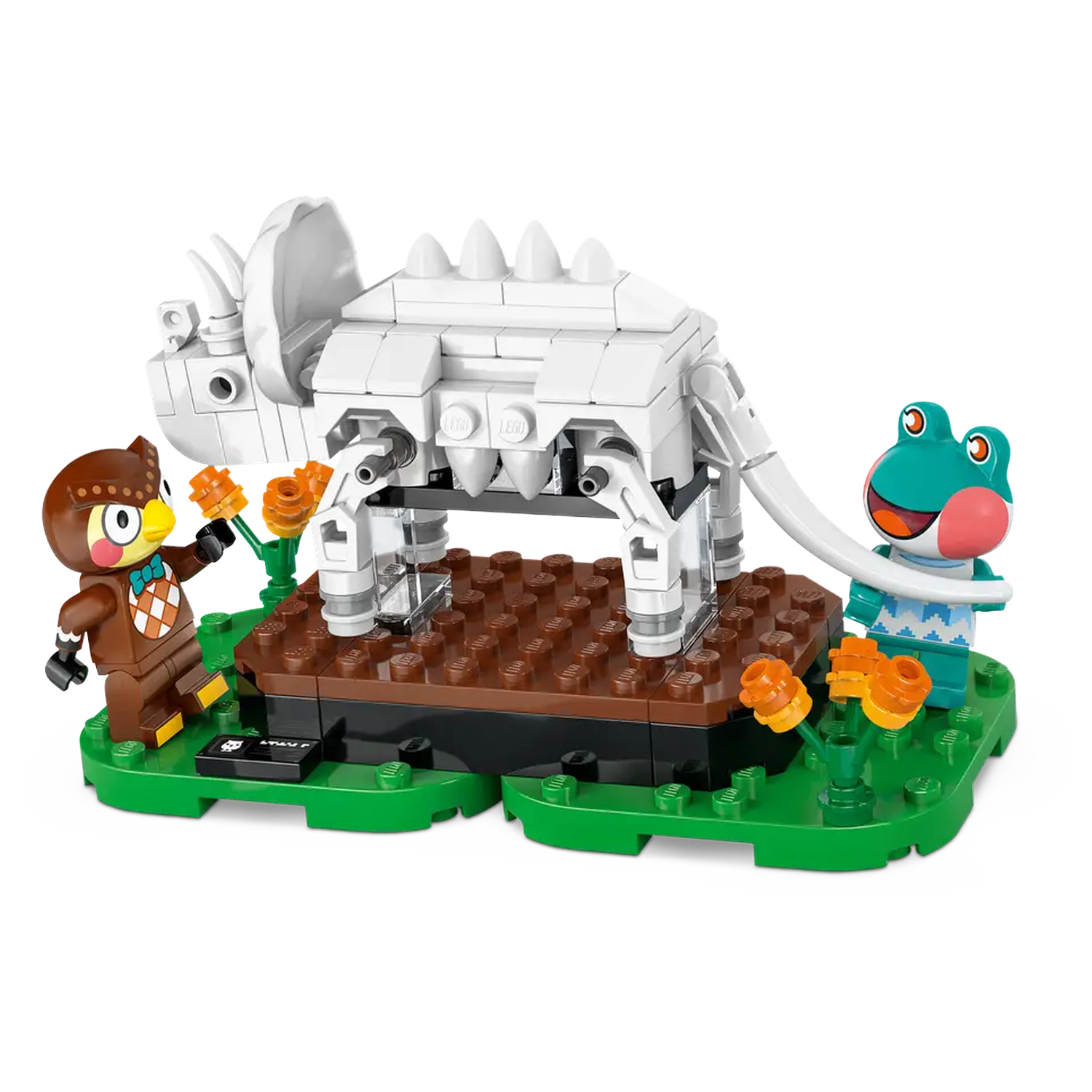 Lego-set met een wit dinosaurus skelet, uil en kikker figuren, oranje bloemen, allemaal op een groene basis.