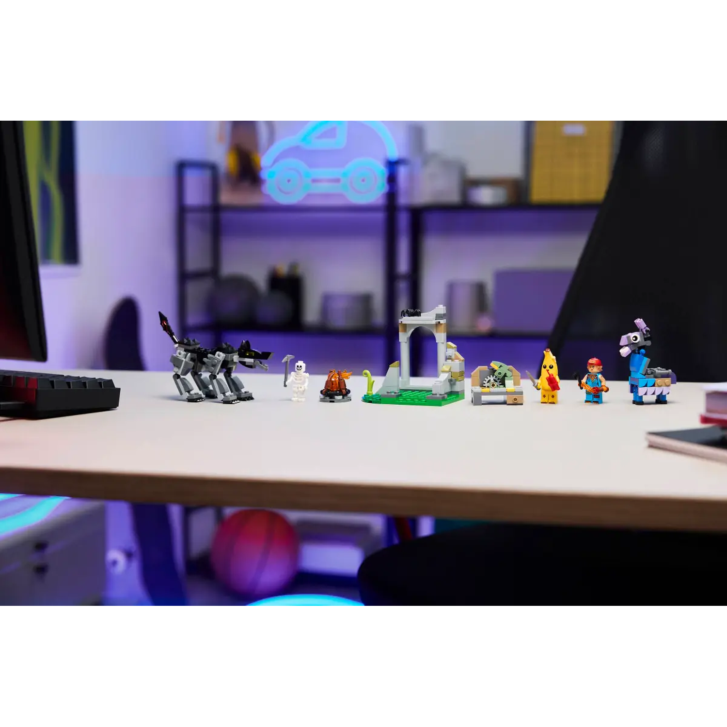 A desk with Lego figures. A gray wolf, a skeleton, a bonfire, a building, a banana, a person, and a blue llama are on the desk.